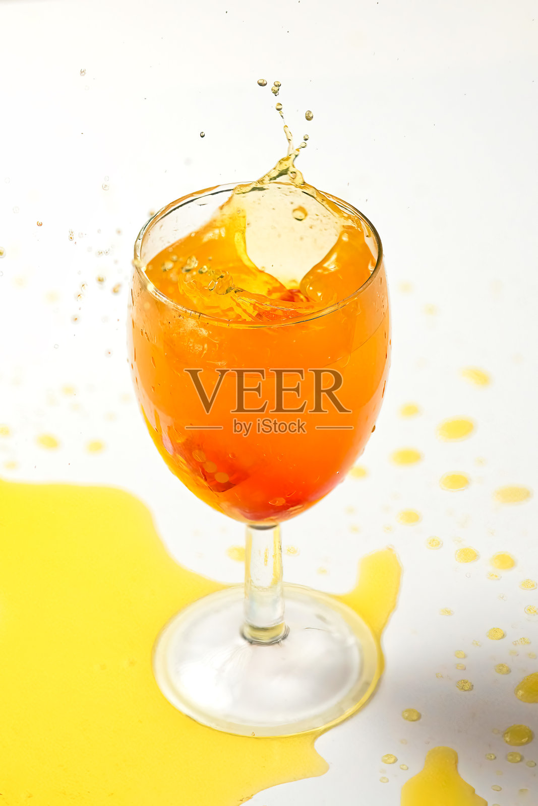 从掷出的骰子中向玻璃杯中泼洒橙色液体。特写白色背景照片摄影图片