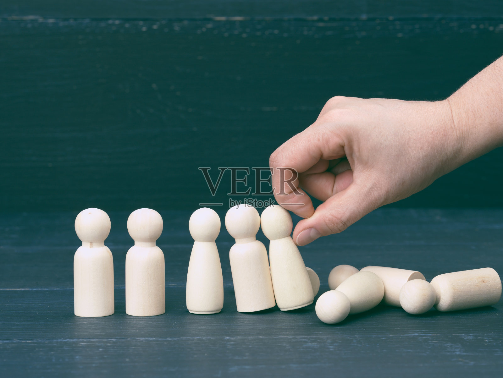 手推着木雕人像，他们倒向不同的方向。心理压力对一个人的概念照片摄影图片