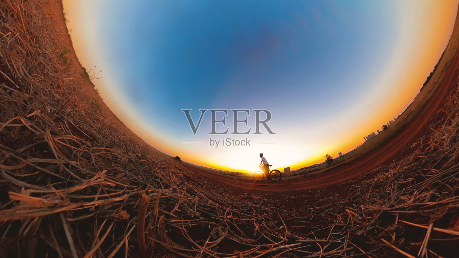 一个戴着头盔和眼镜的黑人在日落时分骑着自行车。空间的文本。照片摄影图片