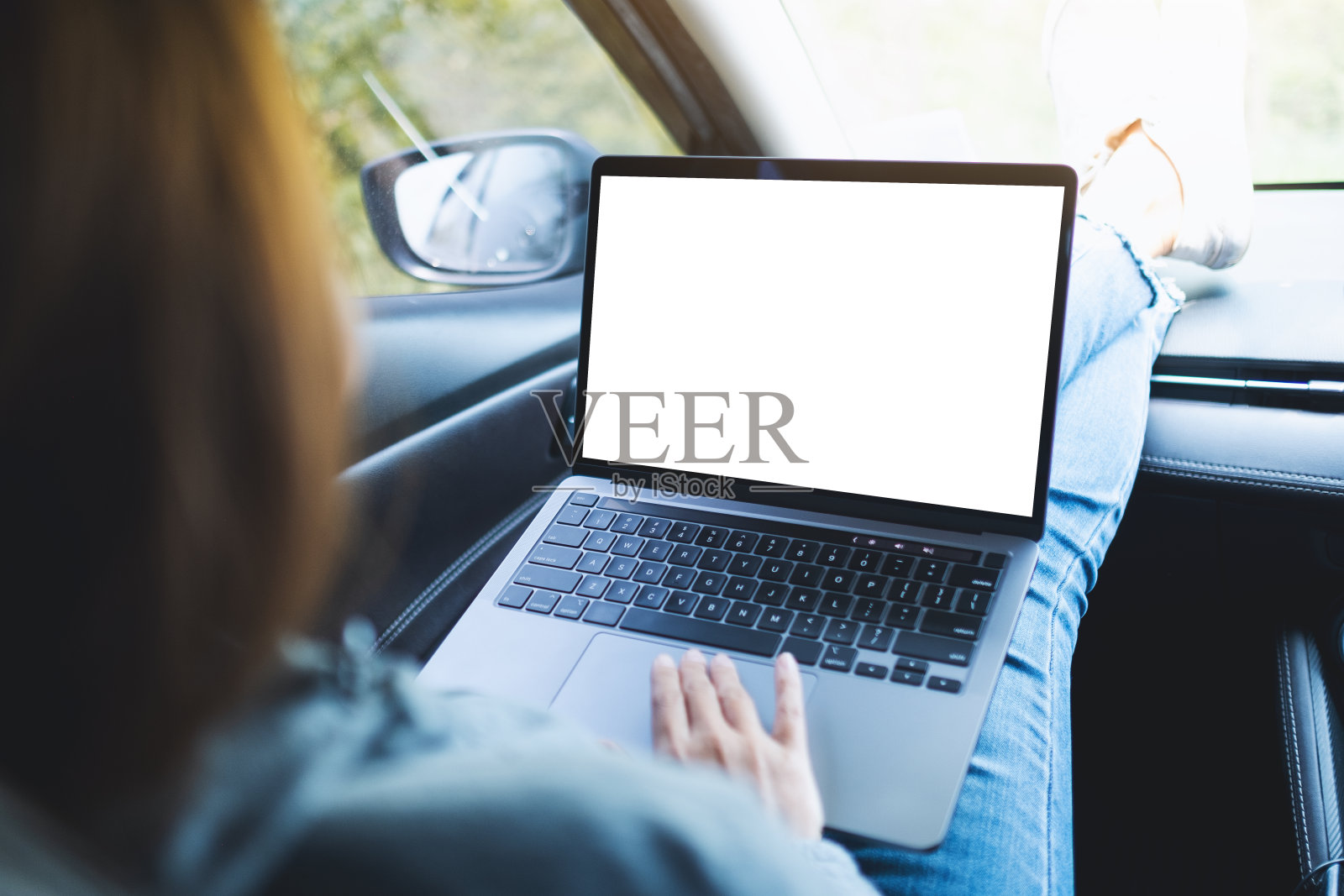 一位女士在车里用笔记本电脑工作，桌面是空白的照片摄影图片