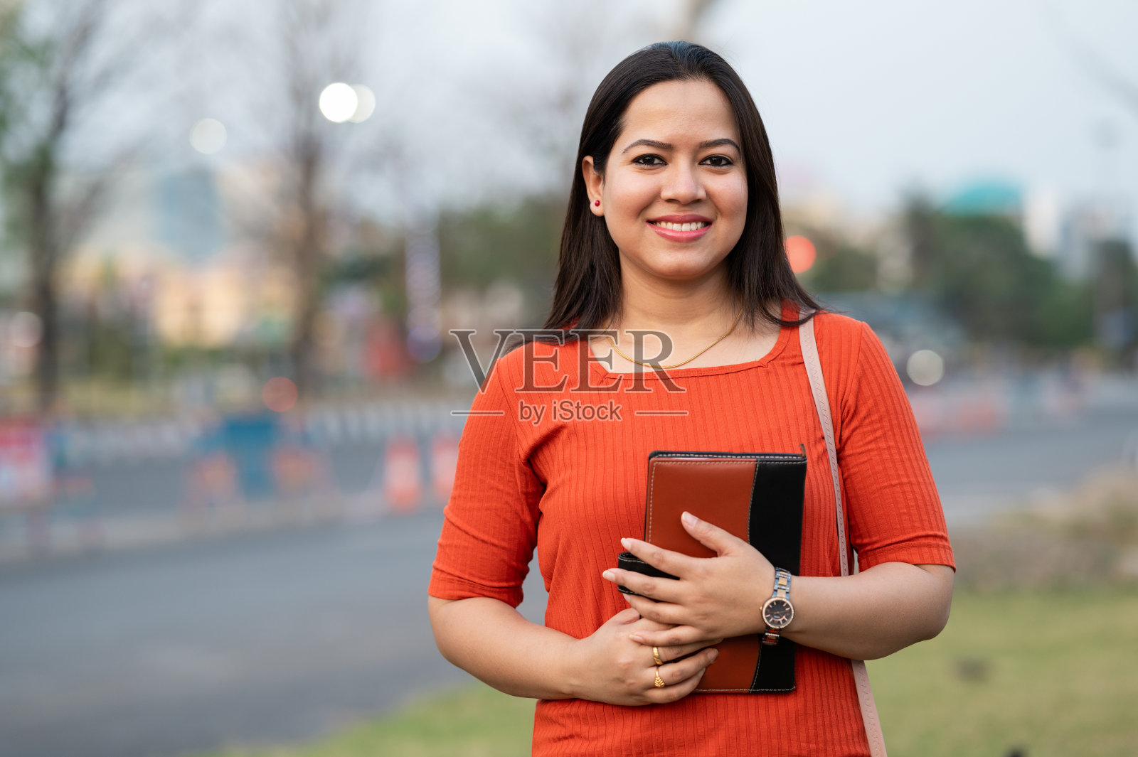 美丽的印度少女看着相机，拿着一本书。照片摄影图片