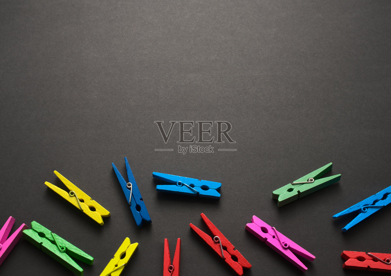 迷你彩色的工艺木钉平铺在黑色的黑色垃圾纹理图案抽象的背景上。为你的设计腾出空间。俯视图，没有人，水平图像风格。照片摄影图片