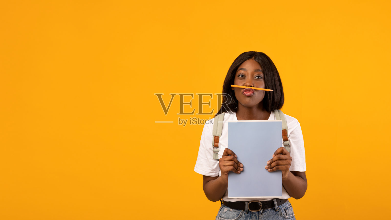 可爱的非洲裔美国女学生与书在黄色照片摄影图片