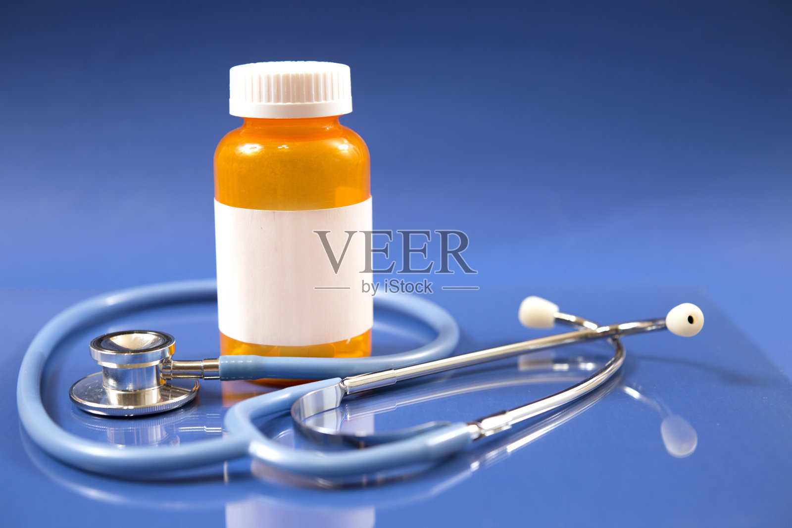 蓝色背景的药瓶和听诊器。照片摄影图片