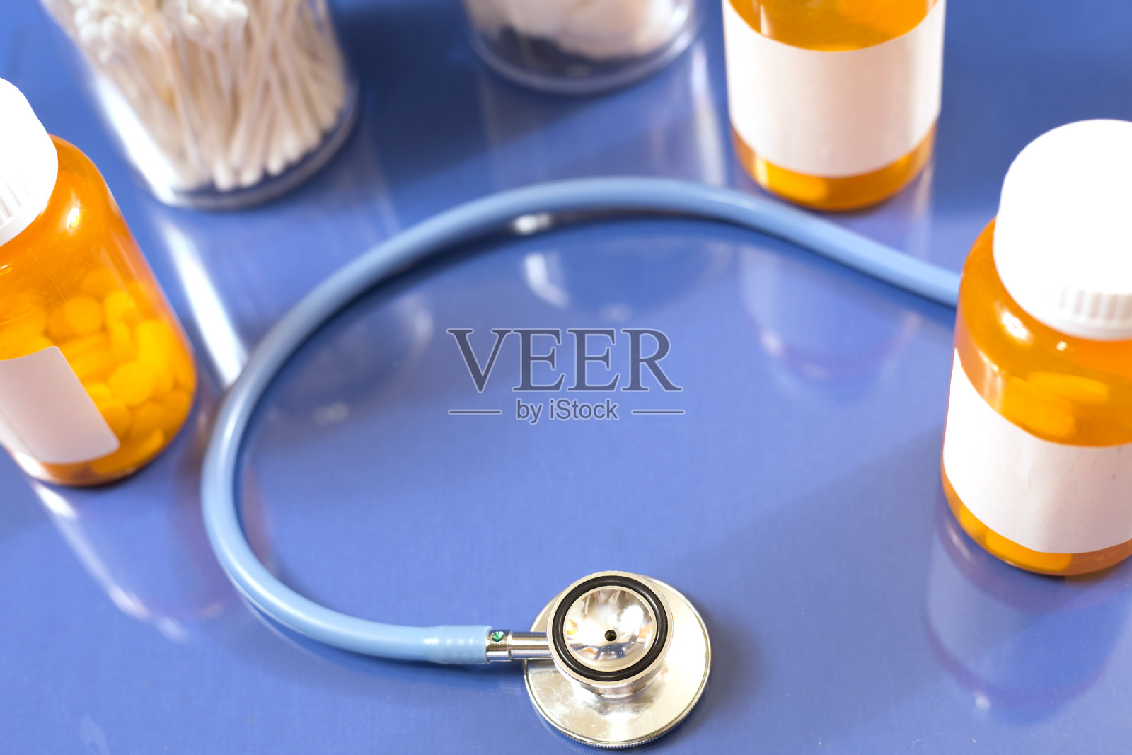 蓝色背景的药瓶和听诊器。照片摄影图片