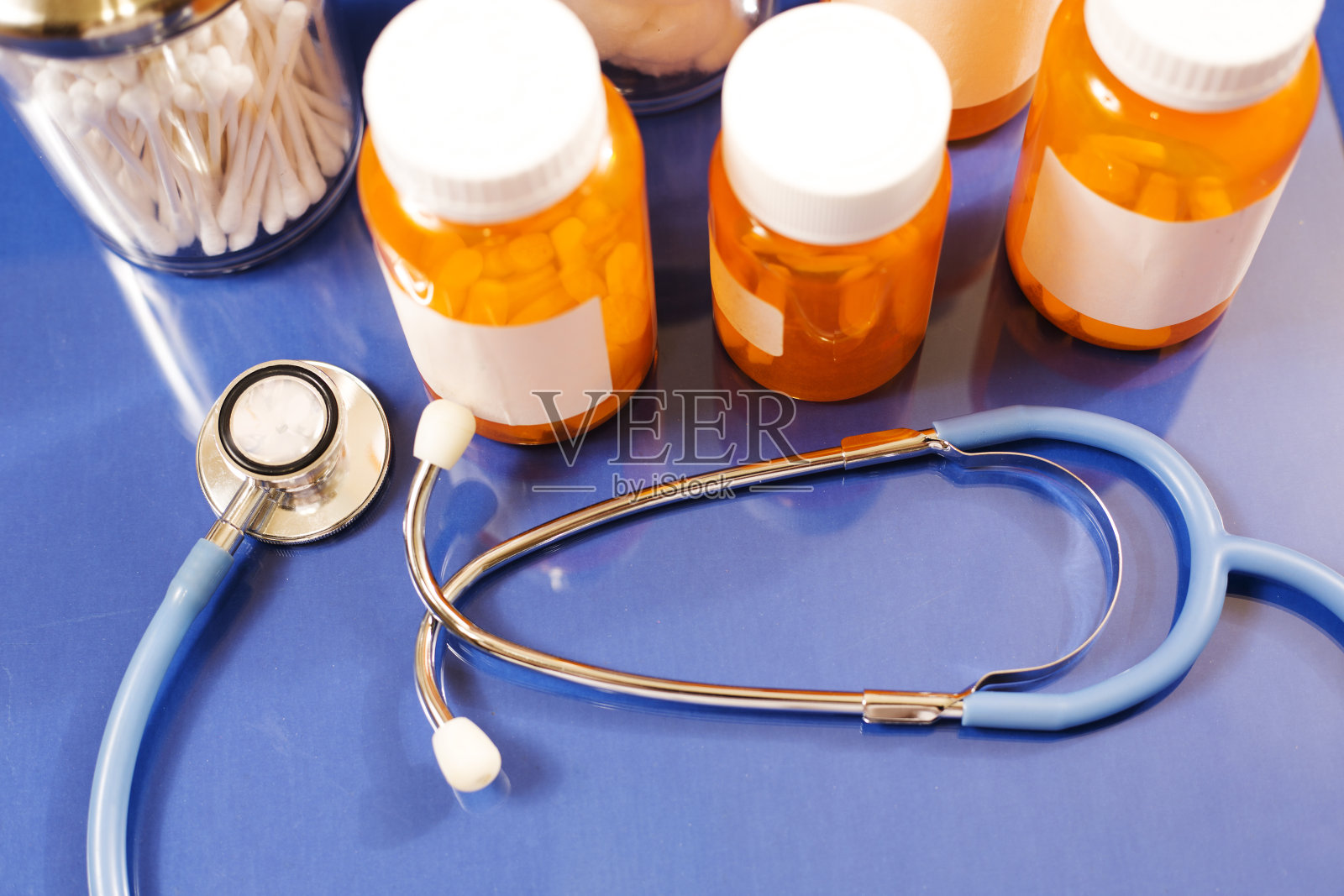 蓝色背景的药瓶和听诊器。照片摄影图片