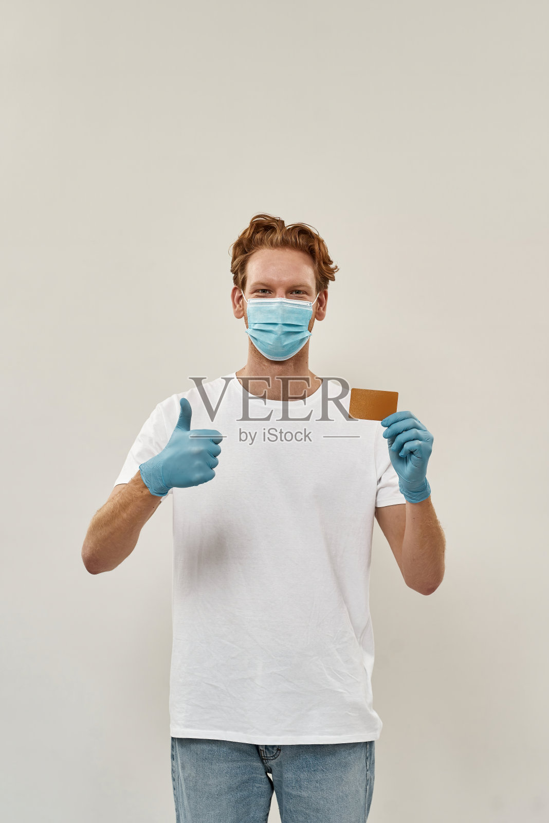 年轻的红发快递员竖起大拇指，并宣传信用卡安全支付照片摄影图片