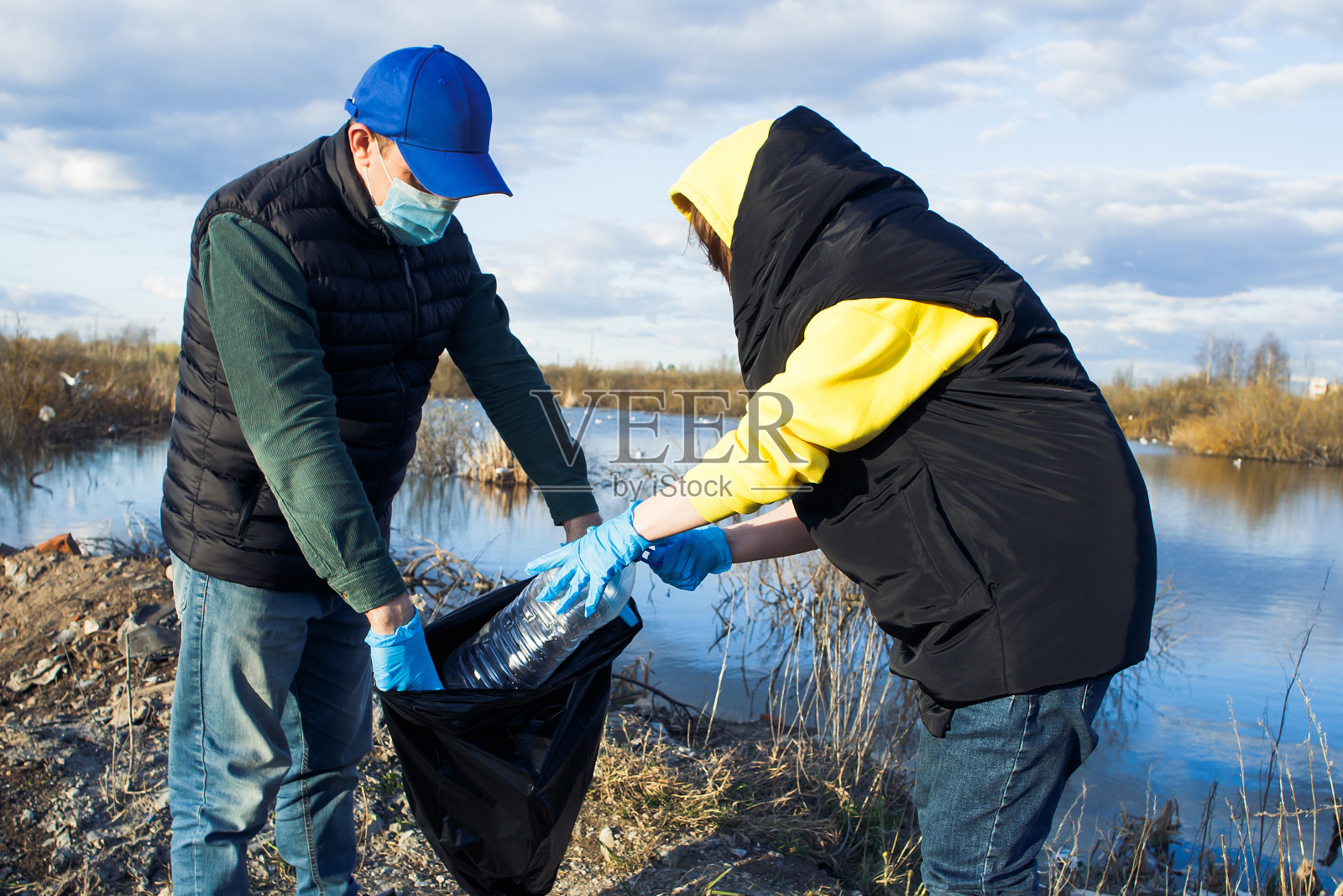 志愿者们在河岸上收集袋装塑料瓶，宣扬生态和保护土地的理念照片摄影图片