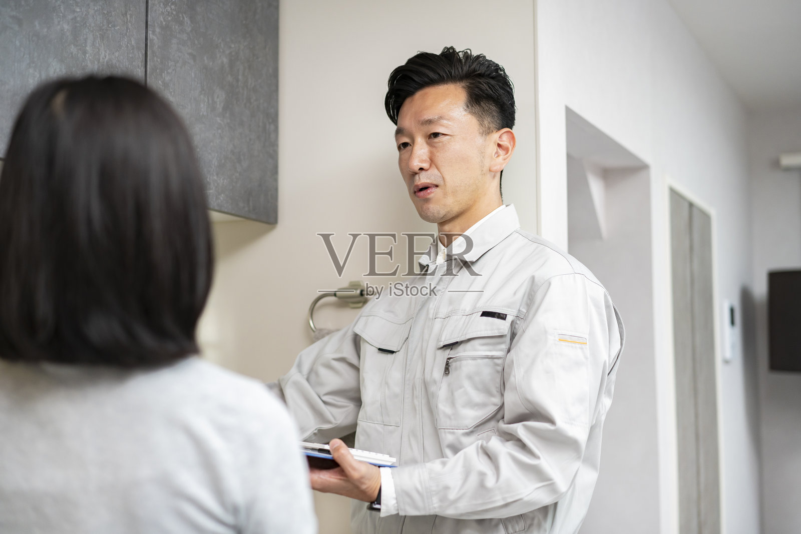 一个穿着工作服的男人在厨房向一个女人解释照片摄影图片