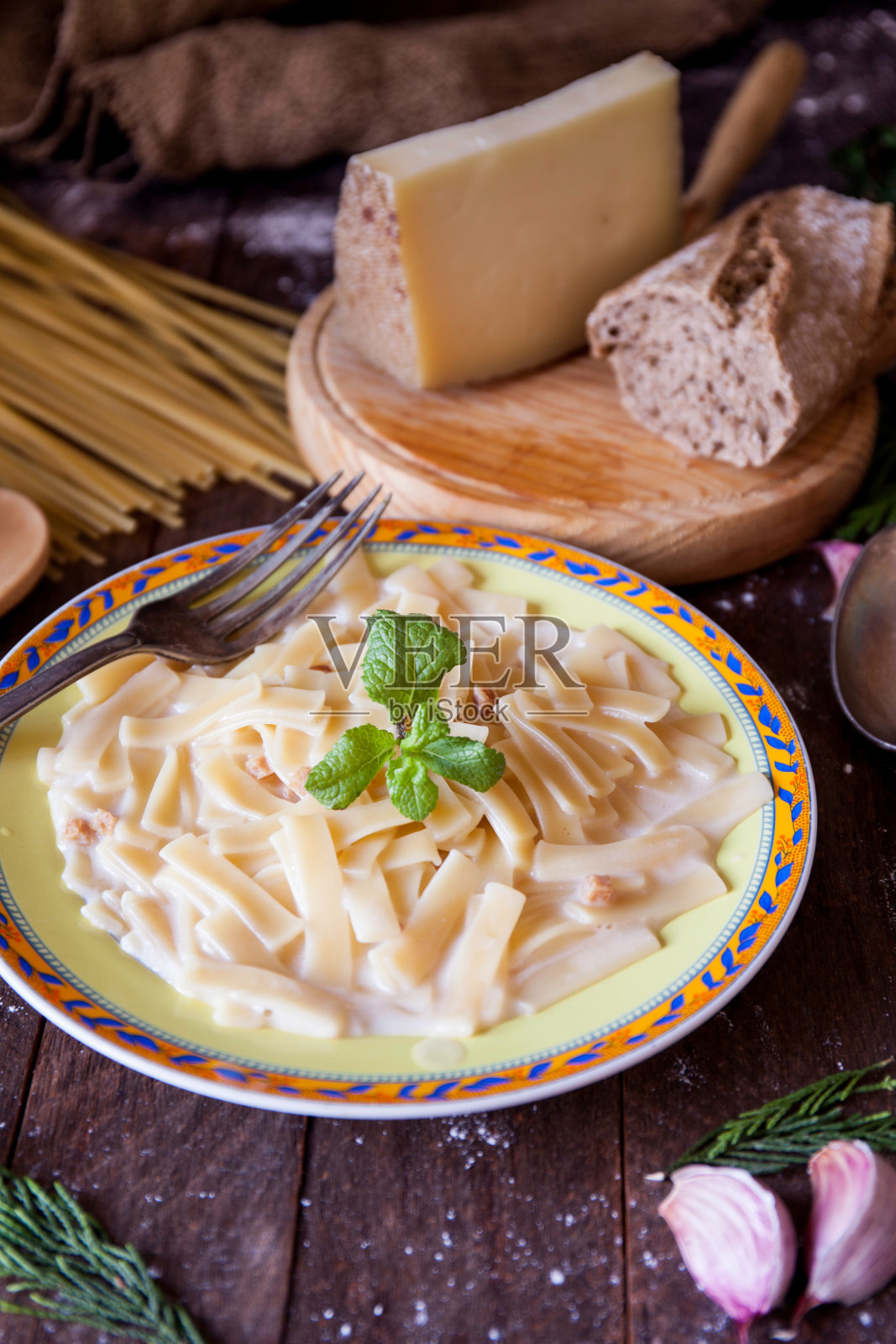 这是一张质朴的桌子上的干酪意面，厨房餐具，奶酪，面包和大蒜照片摄影图片