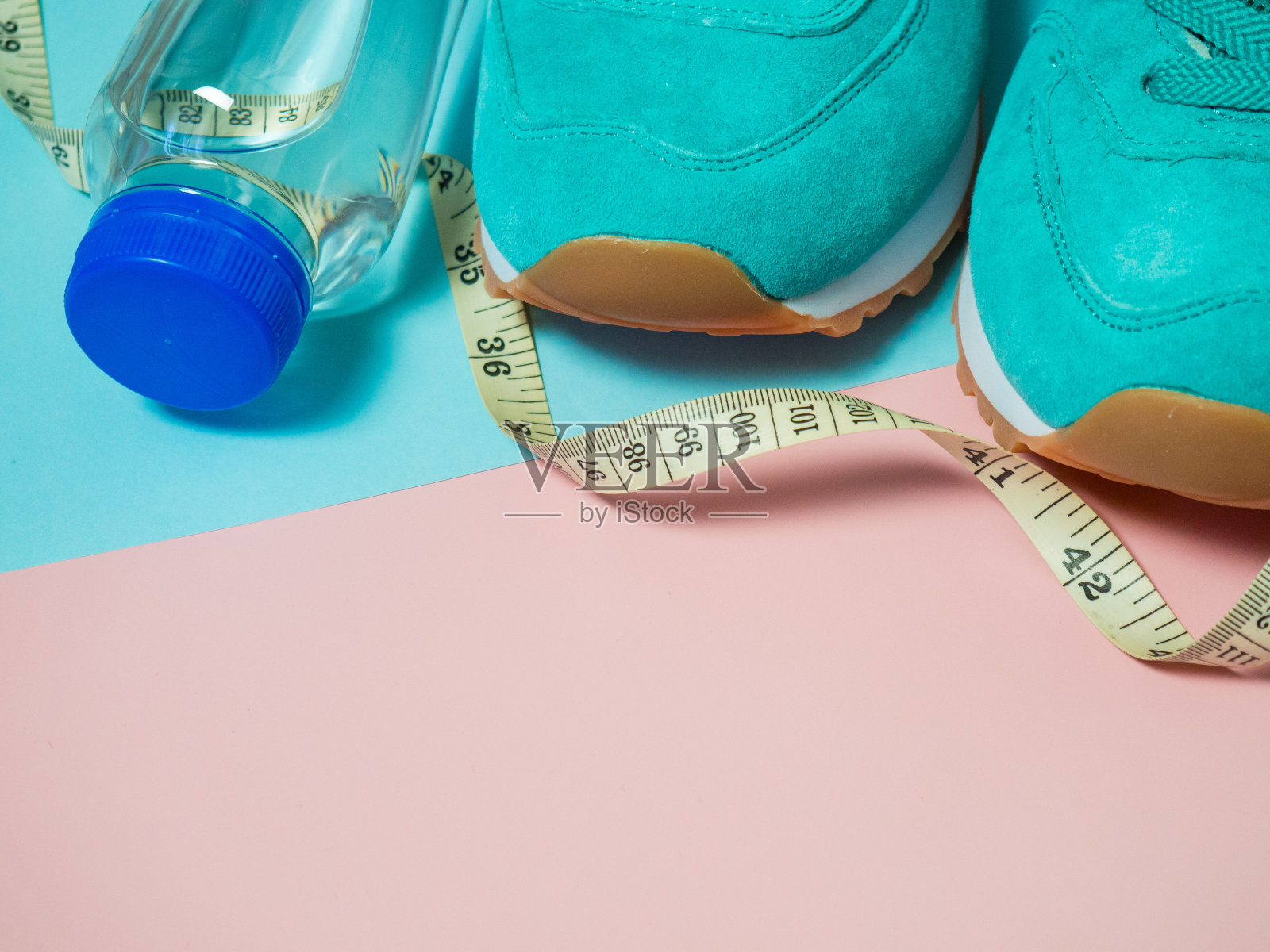 蓝绿色运动鞋和一瓶水在粉红色的背景。健康生活方式的概念，日常训练和跟踪数字照片摄影图片