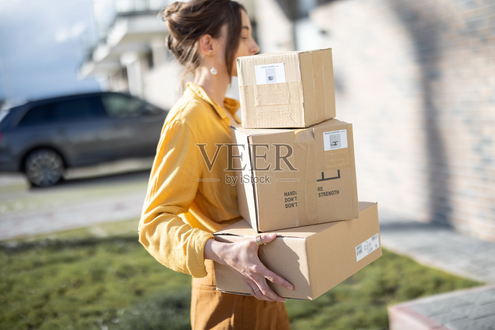 一个女人拿着包裹走在房子前面的街道上照片摄影图片