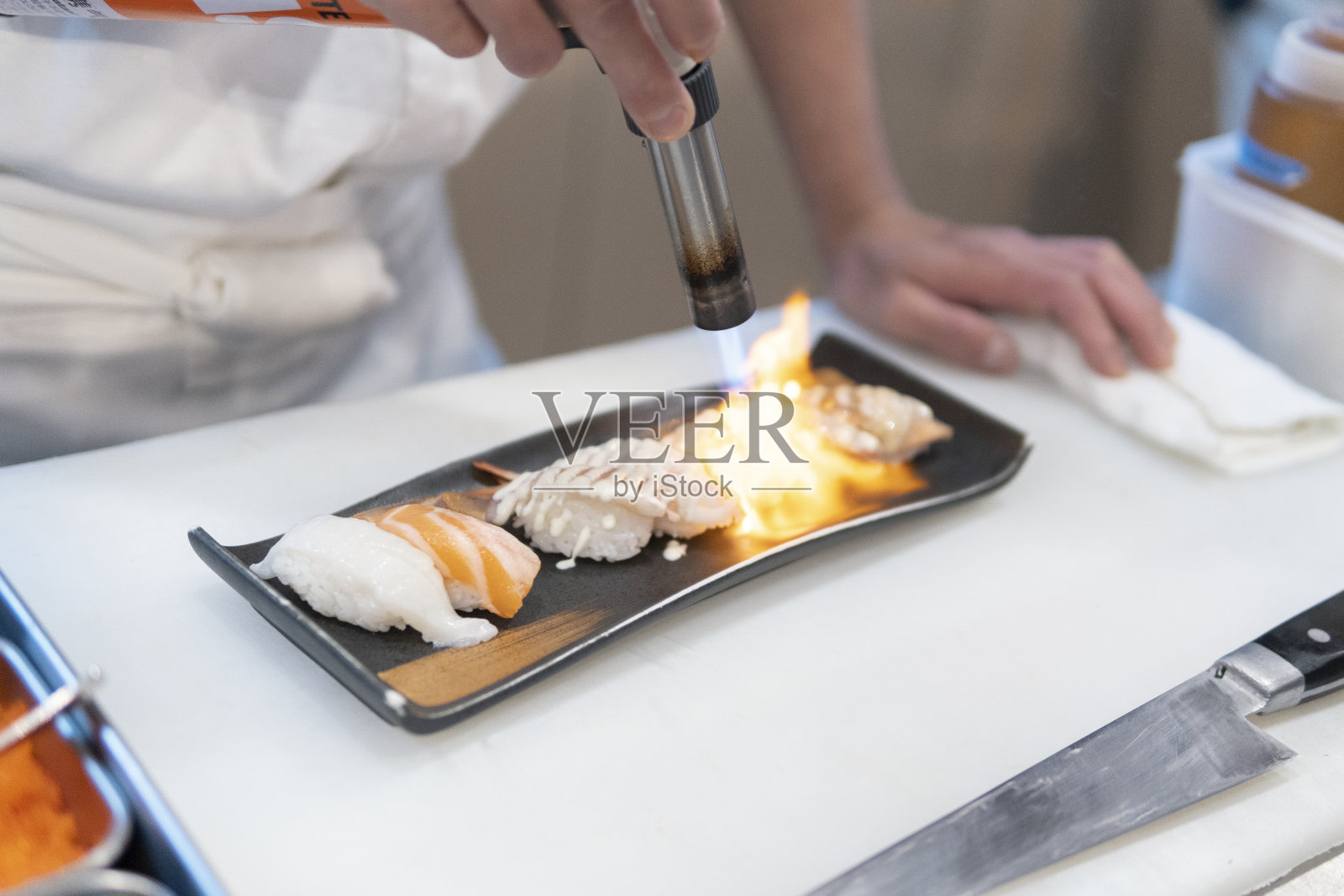厨师正在用喷枪烤生鱼片寿司照片摄影图片