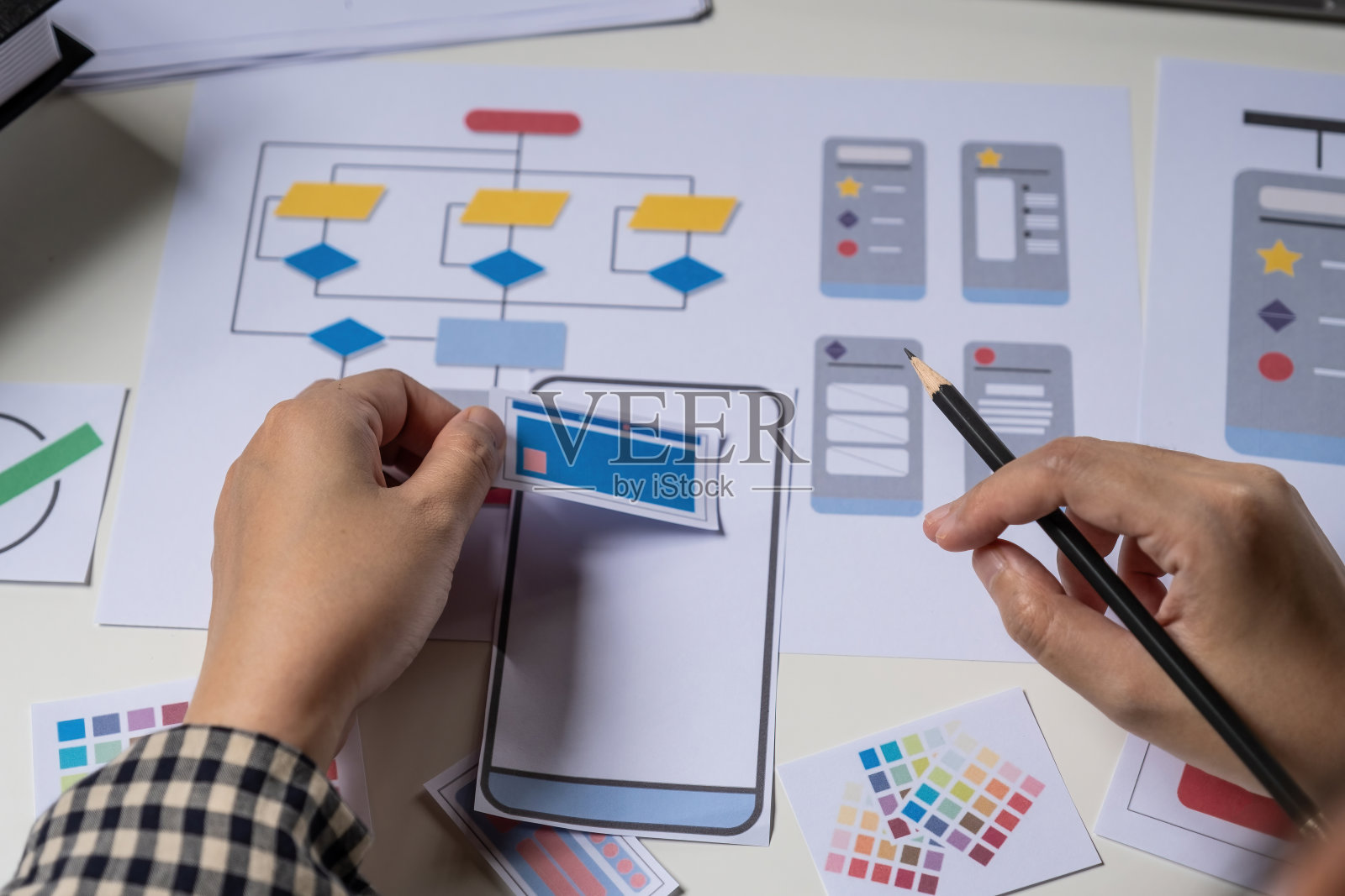 后视图的开发者ux和ui设计师关于手机应用程序和选择一些界面模拟手机。创意数字发展机构概念。照片摄影图片