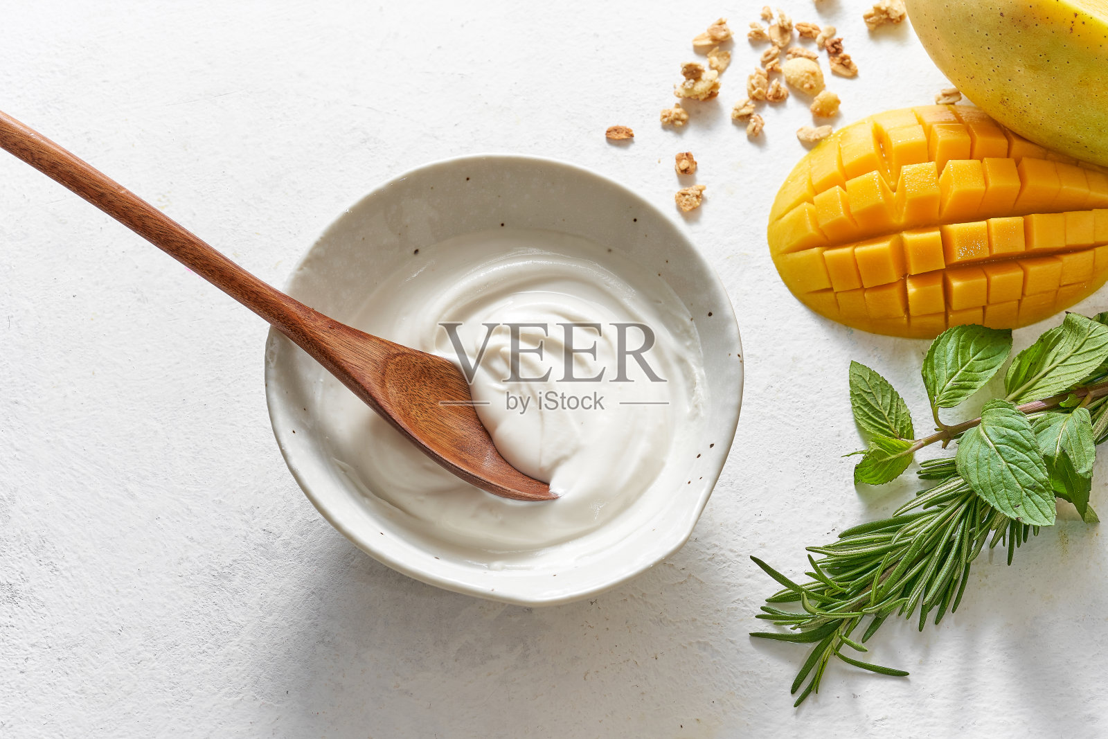 自制早餐新鲜多彩的装饰混合酸奶格兰诺拉与芒果，无花果，谷类，迷迭香，薄荷在白色的背景照片摄影图片