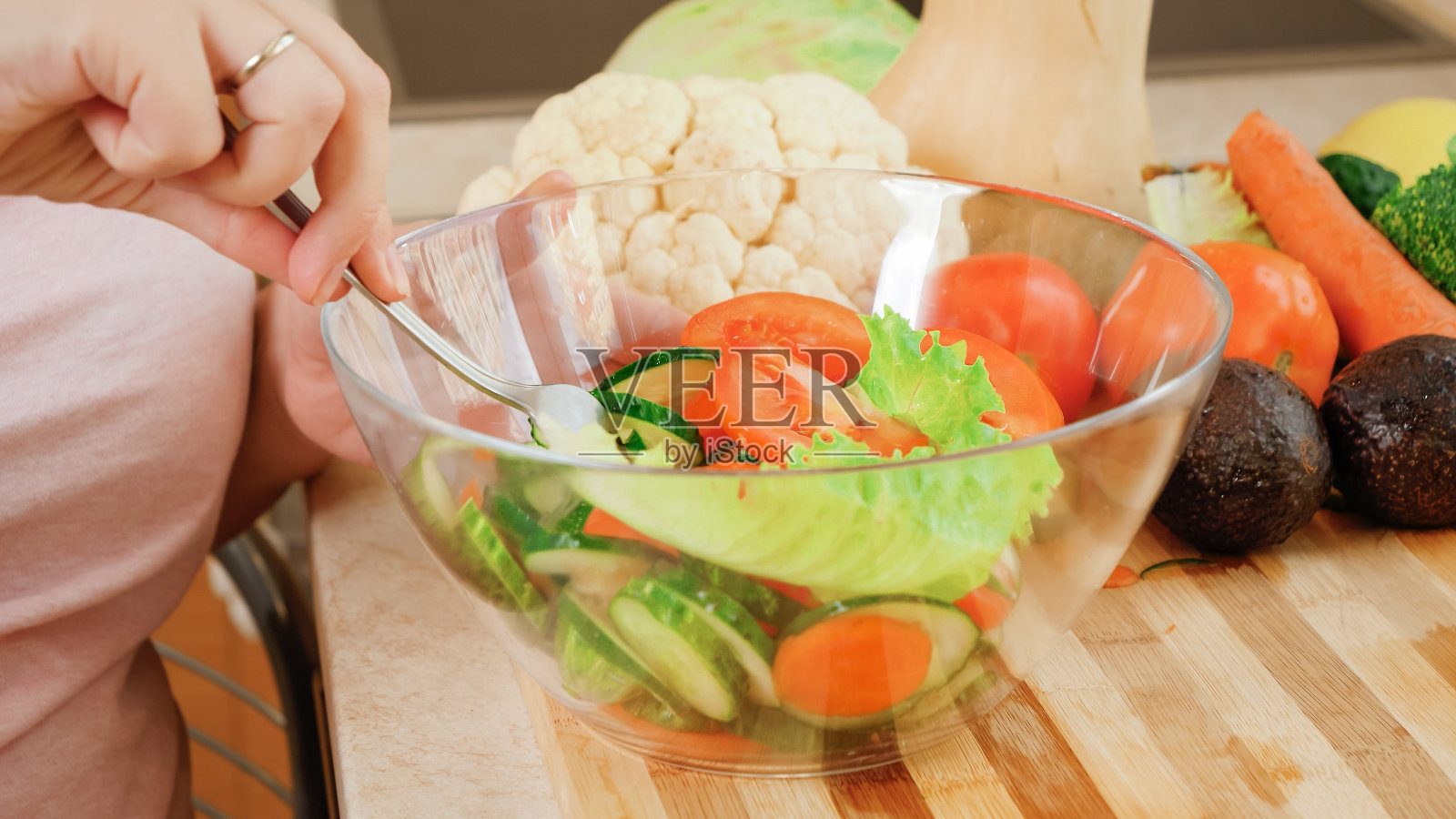 年轻孕妇在厨房里混合新鲜美味的沙拉蔬菜的特写镜头。怀孕期间健康生活方式和营养的概念照片摄影图片