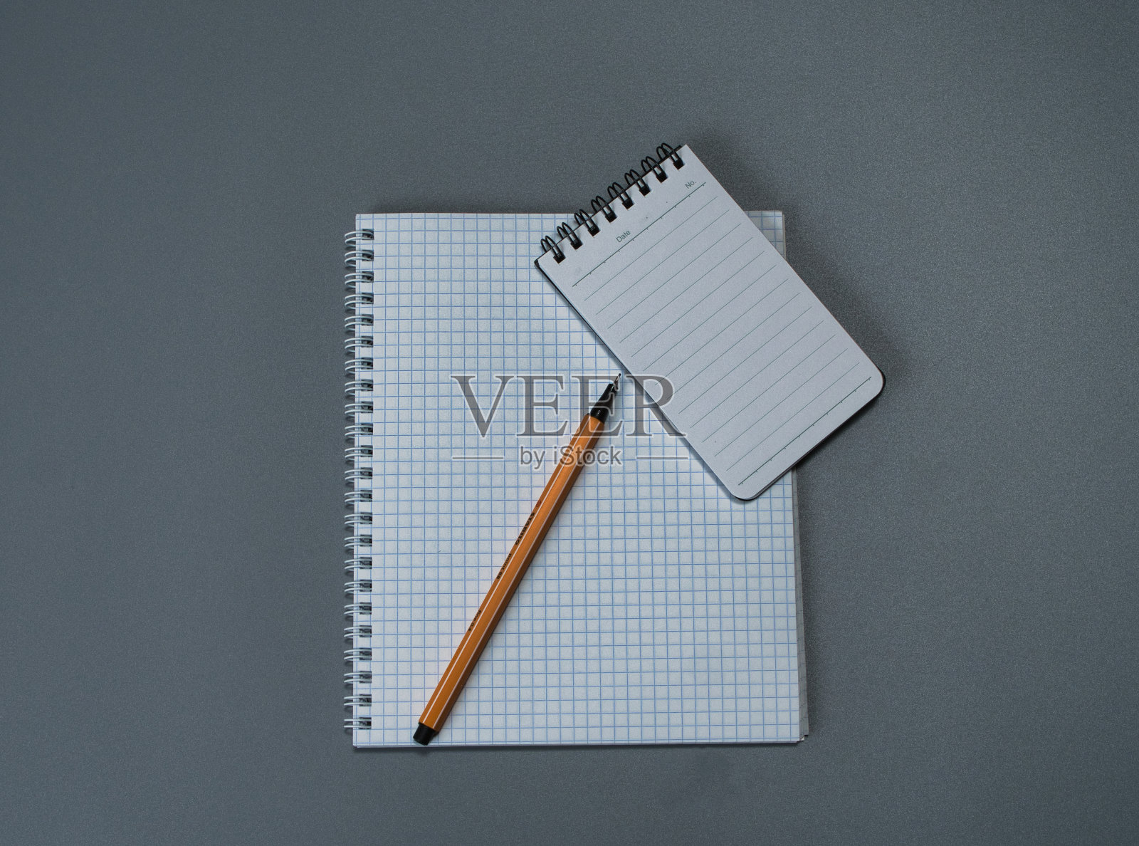 灰色背景上的方格笔记本和钢笔照片摄影图片