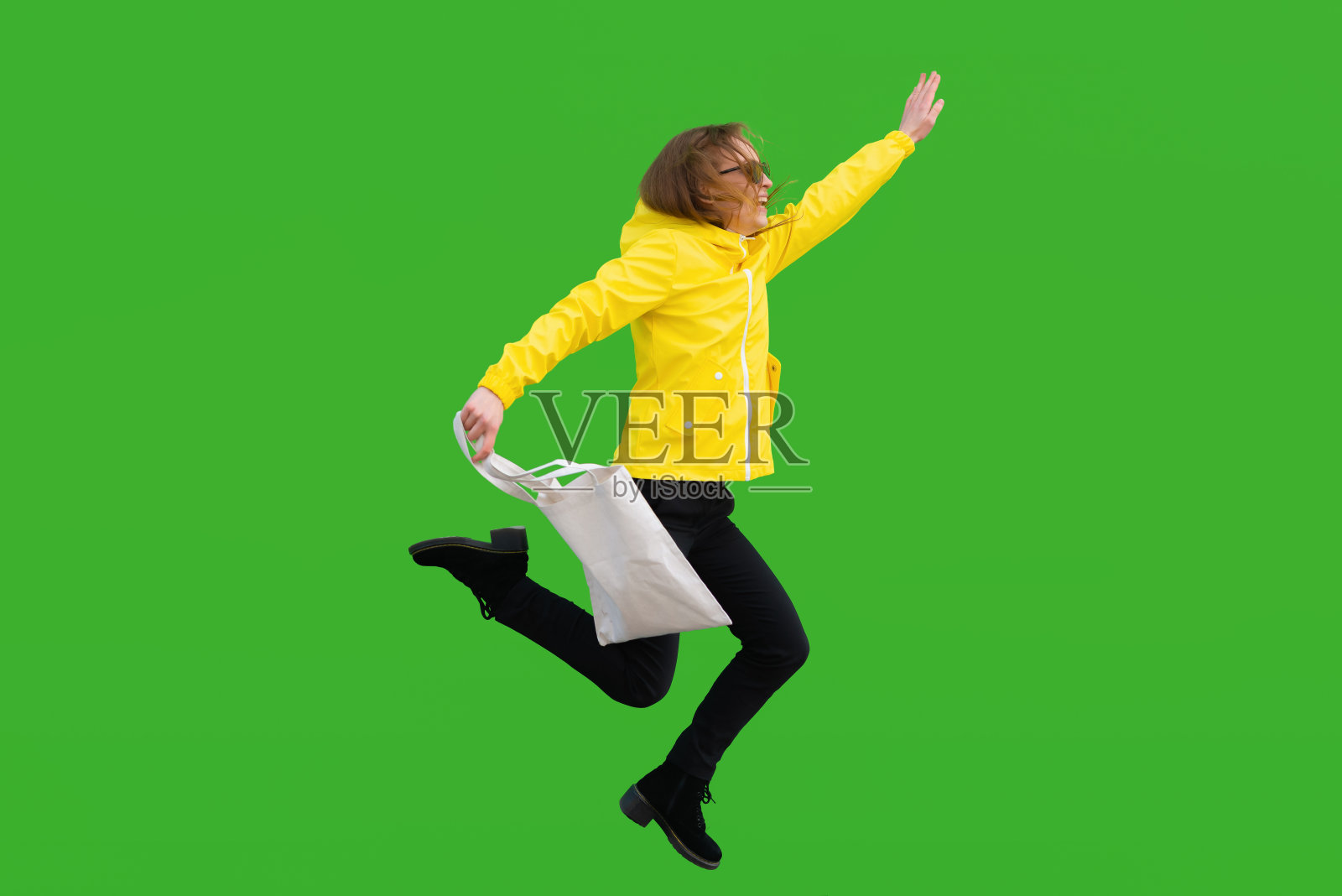 穿雨衣的女孩跳了起来，微笑着举起了手照片摄影图片