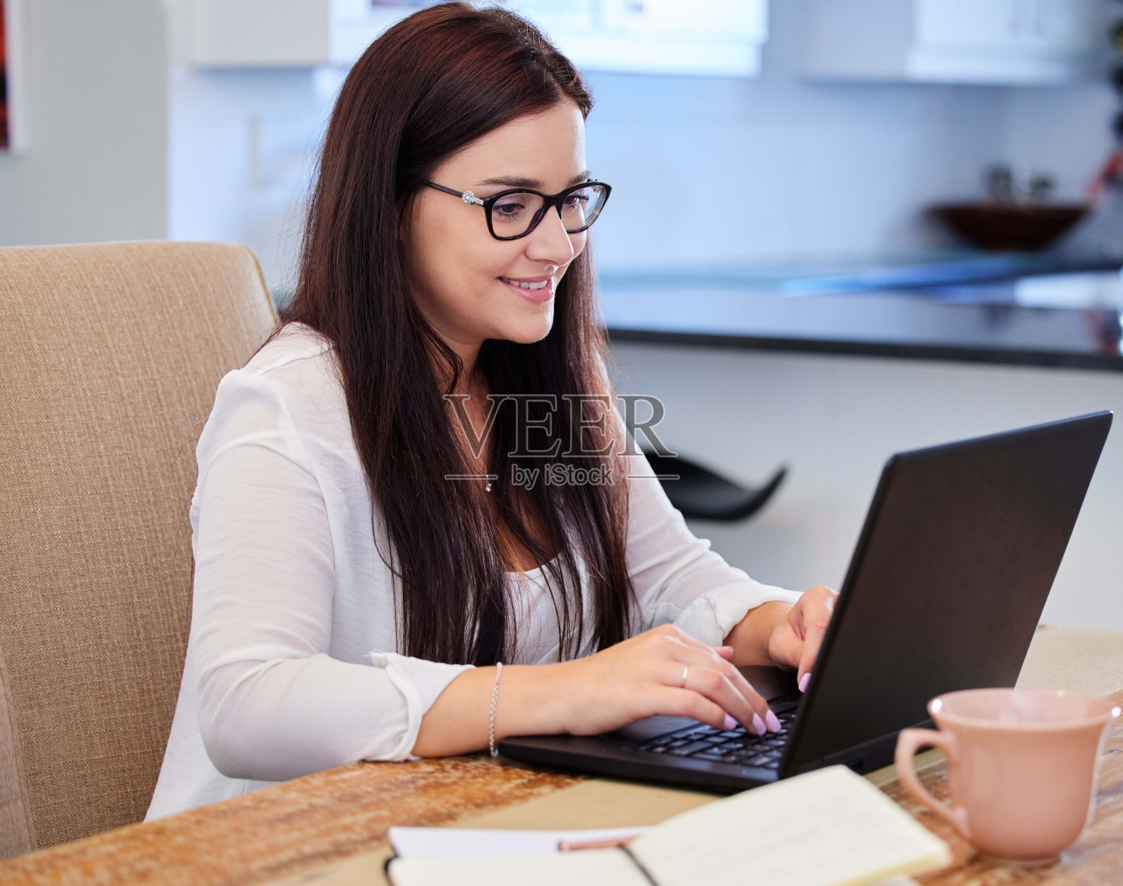 一名年轻女子坐在桌子旁使用笔记本电脑的照片照片摄影图片
