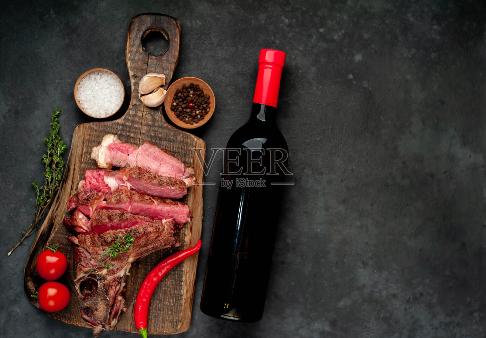 烤牛排和酒瓶与玻璃在石头背景照片摄影图片