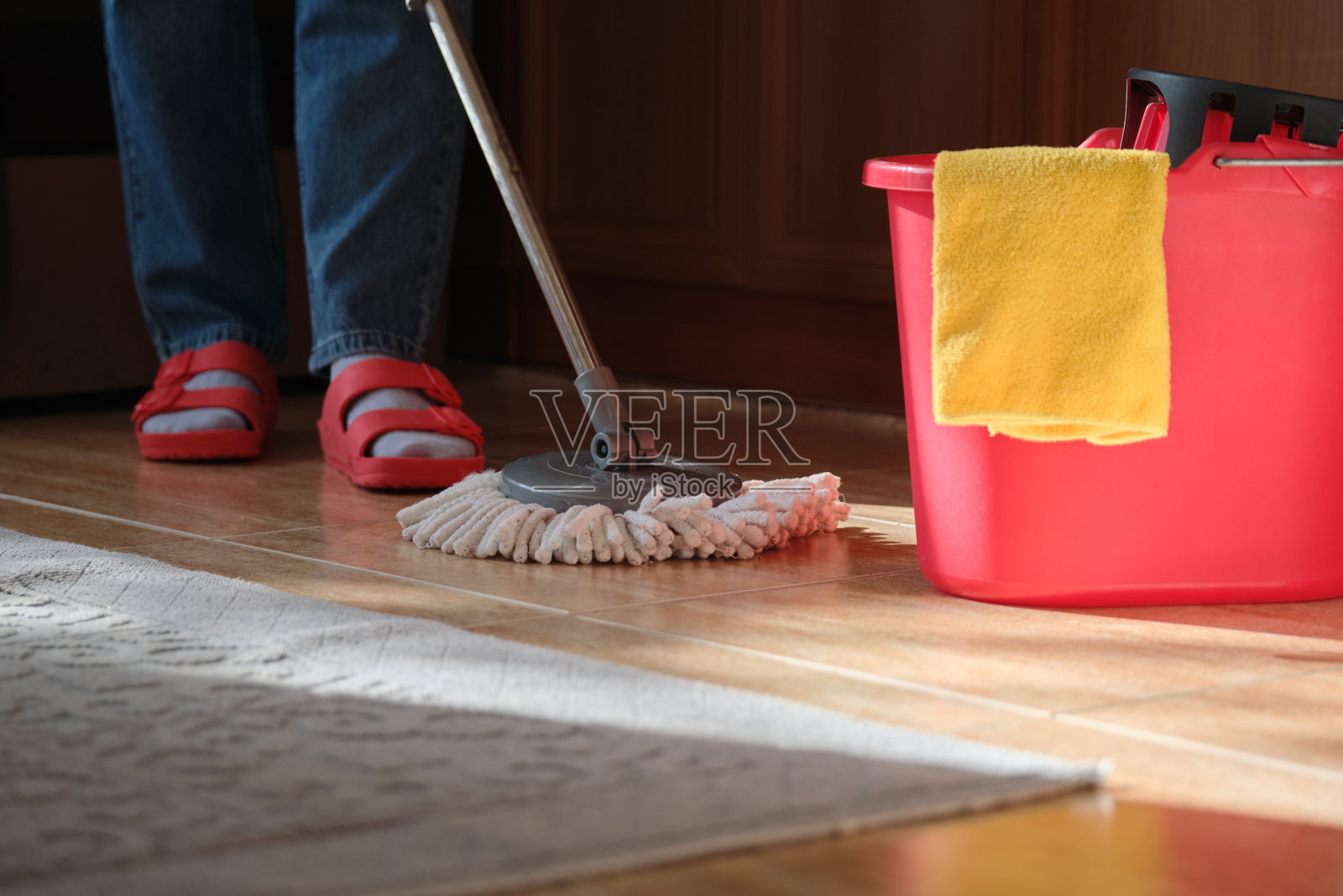 打扫屋子。一个女人在厨房里用拖把和一桶水拖地照片摄影图片