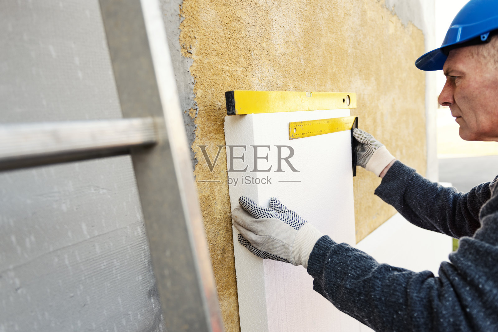 建筑工人在建筑工地的墙壁上放置聚苯乙烯保温板照片摄影图片