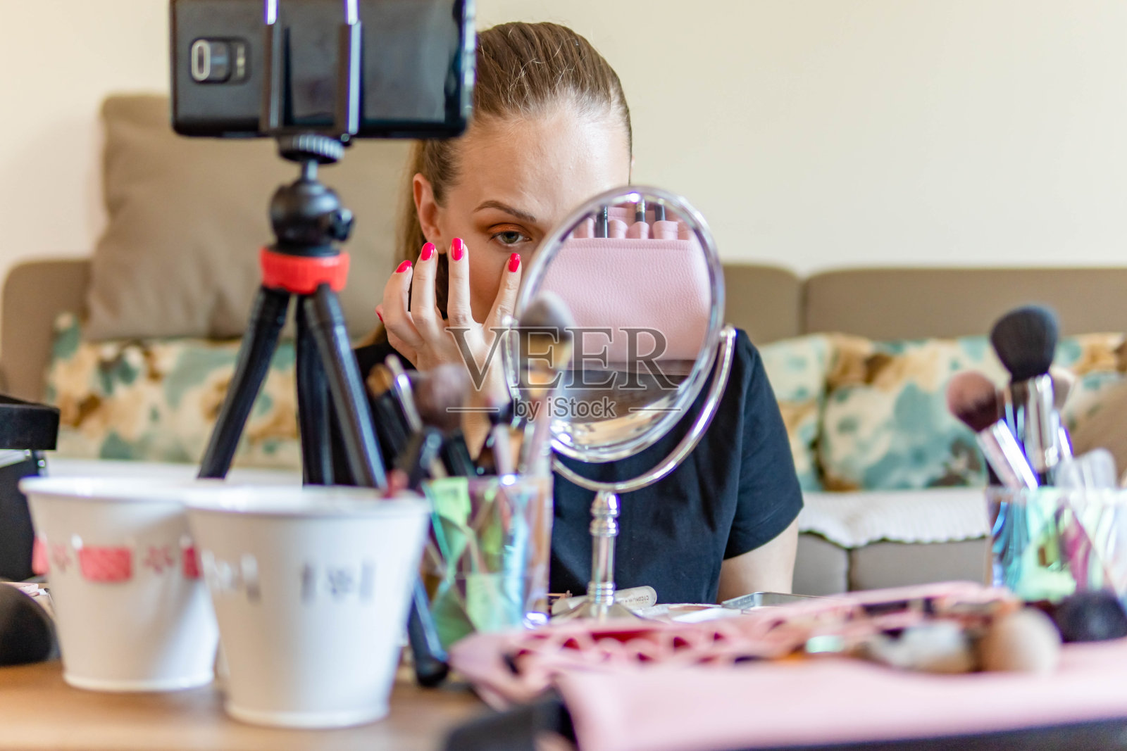 一名年轻女子在智能手机上录制关于化妆品的视频，展示和展示化妆品。她正在用摄像机录化妆教程照片摄影图片