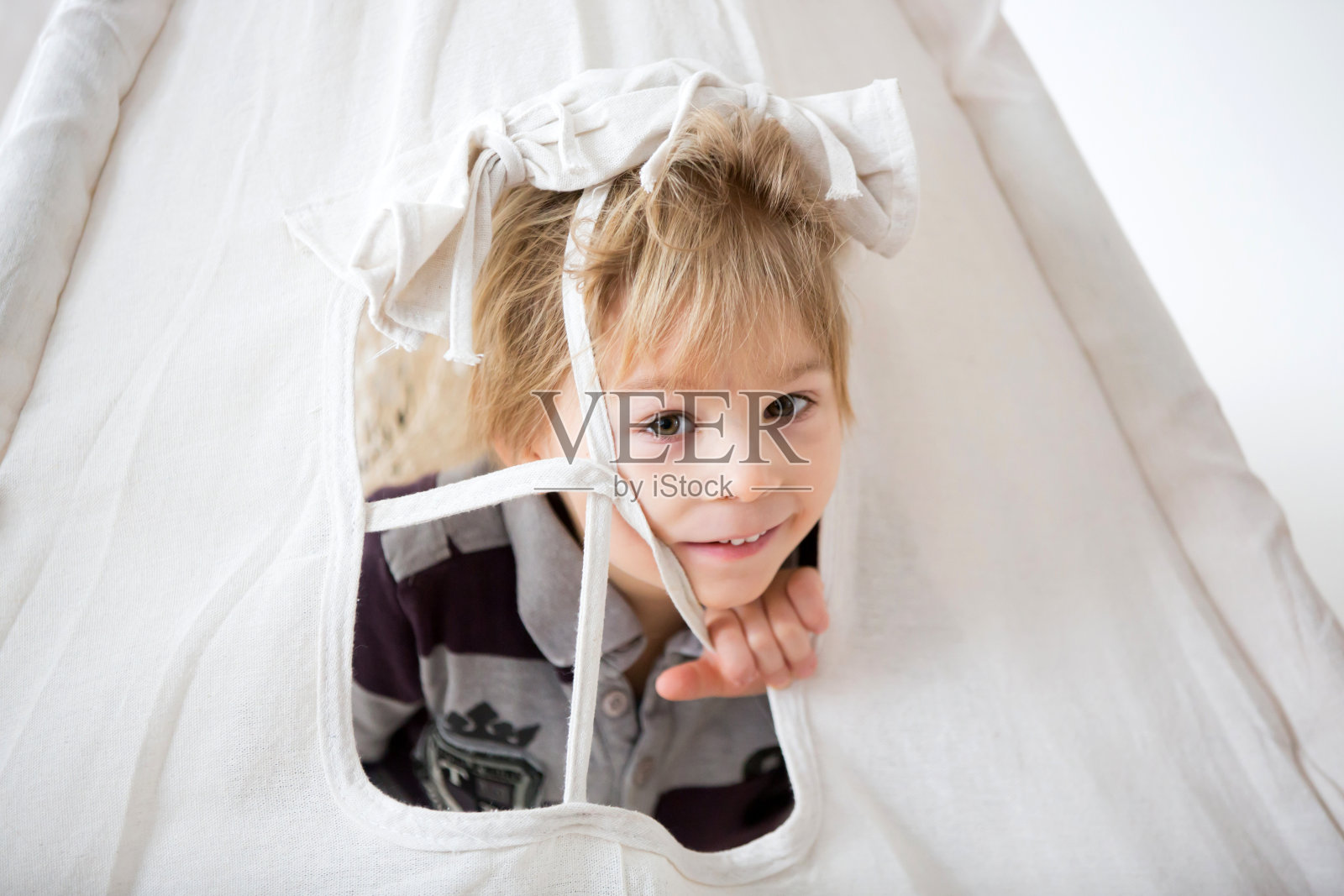 金发的蹒跚学步的孩子，在帐篷里和毛绒猴子玩耍照片摄影图片