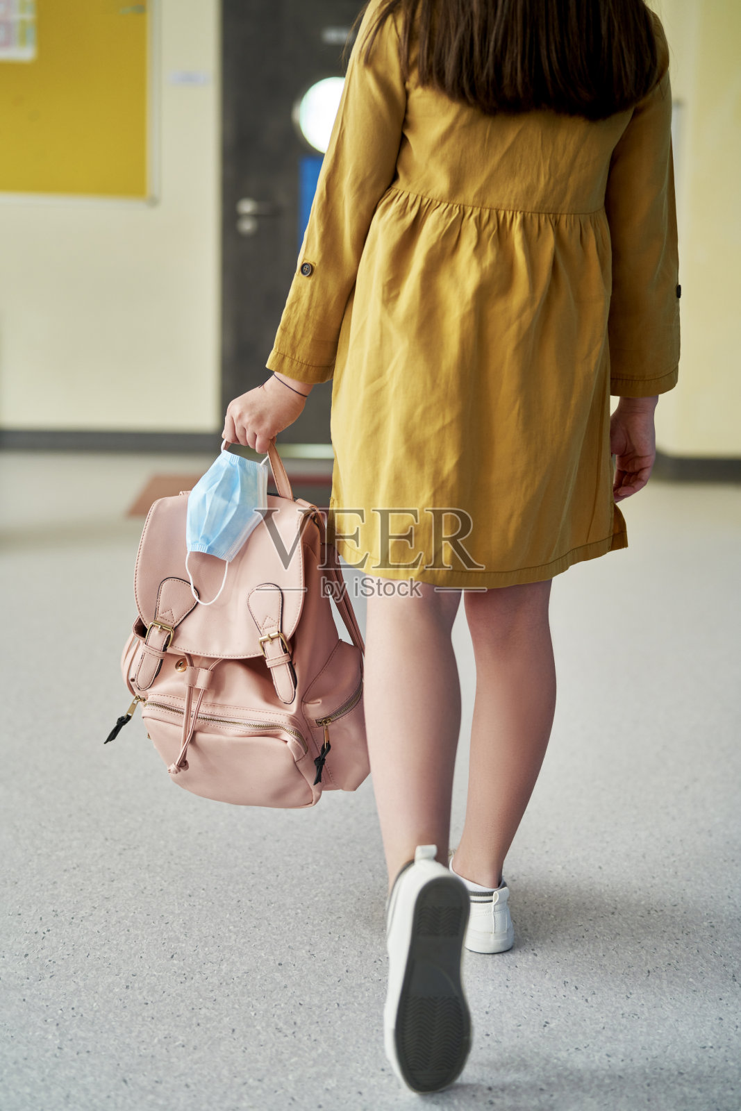 后视图的女学生拿着背包和防护面罩照片摄影图片