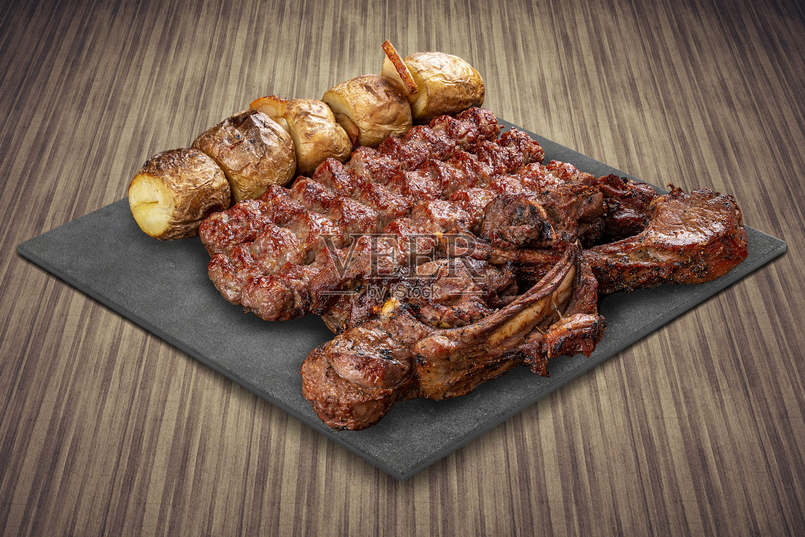 选择各种烧烤美食肉在黑色板与乡村木材背景。羊排，土豆，烤肉照片摄影图片