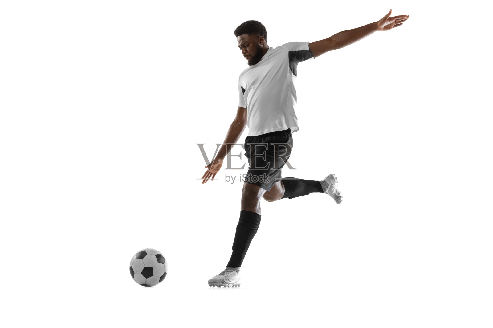 一名非洲男子足球运动员在白人背景下孤立训练。运动、运动、能量和动态的概念。照片摄影图片