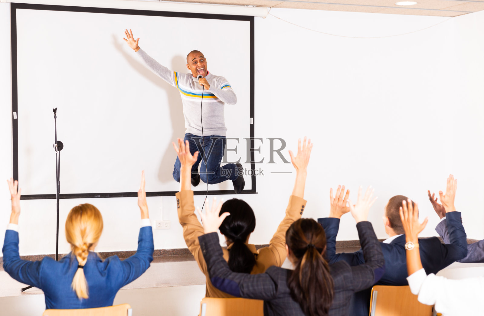 富有表现力的西班牙裔商务教练对观众讲话并跳起来照片摄影图片