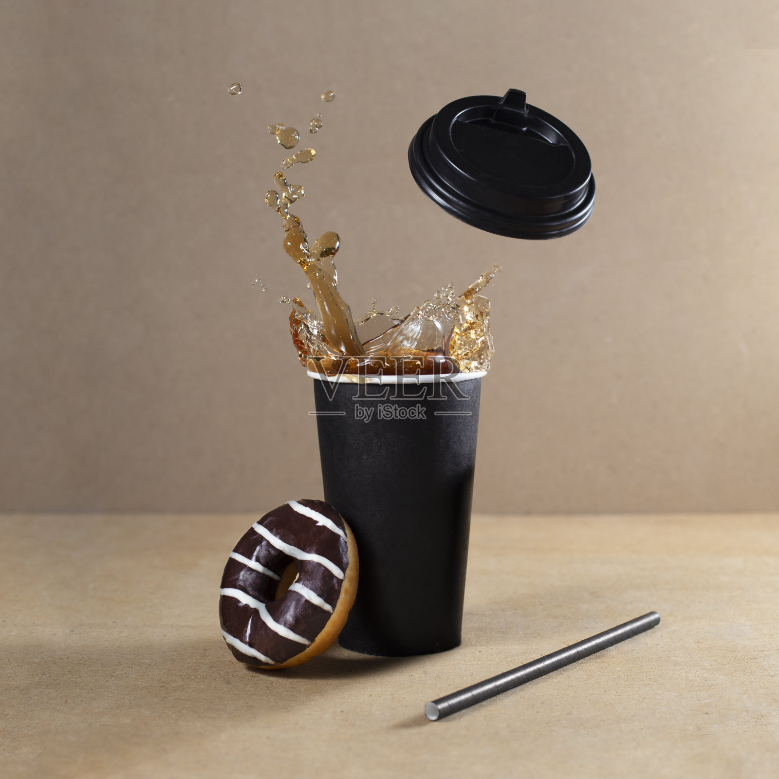 在纸杯里撒上咖啡或茶，在杯子旁边放上巧克力甜甜圈照片摄影图片