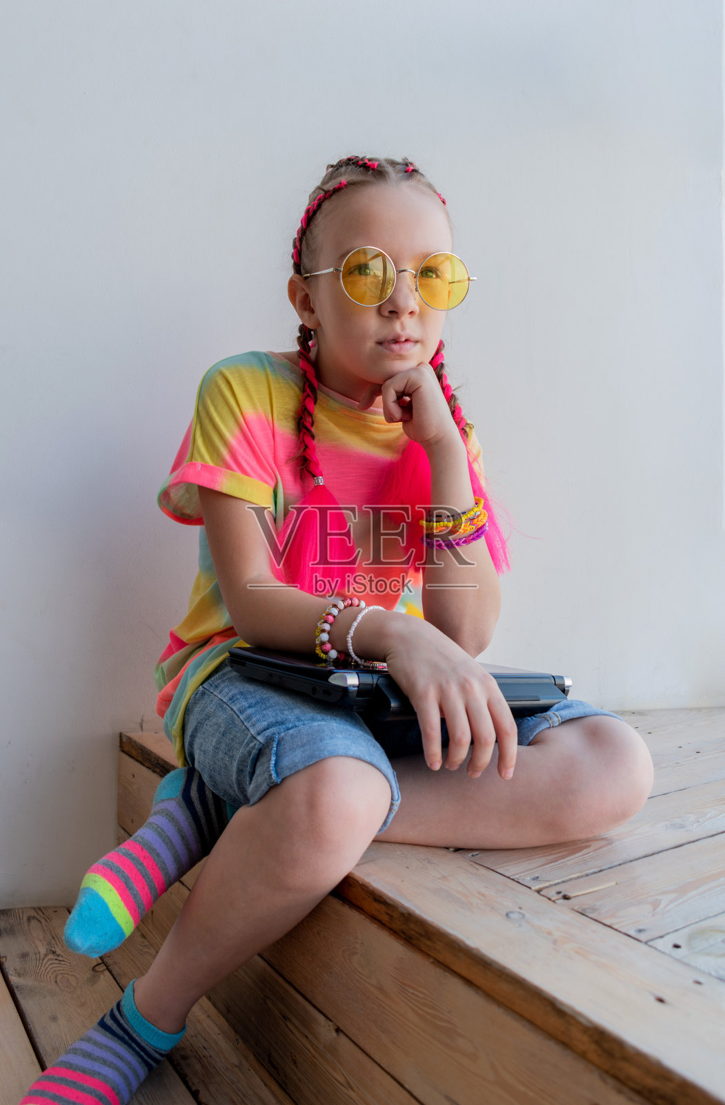 一个十几岁的女孩坐在房子的窗户旁边，一脸沉思。孩子是孤独的。照片摄影图片