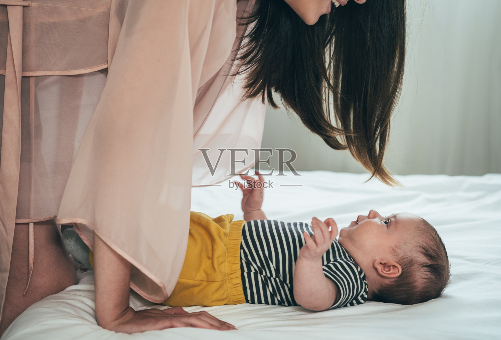 快乐的妈妈和她可爱的宝宝在卧室玩的特写照片摄影图片