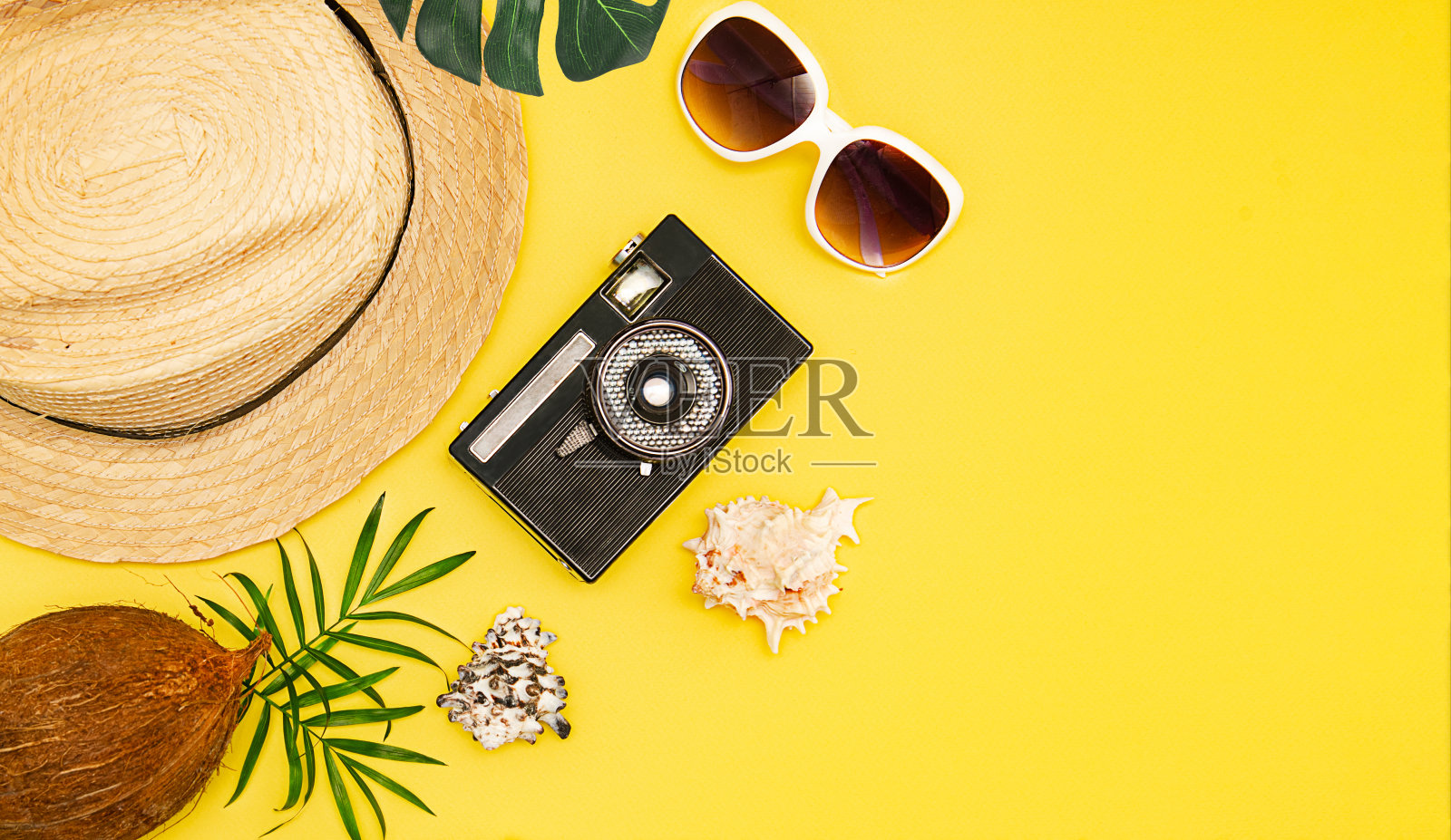 俯视图夏季海滩概念。草帽，太阳镜和相机在黄色的背景。夏季旅行边界框架与拷贝空间照片摄影图片