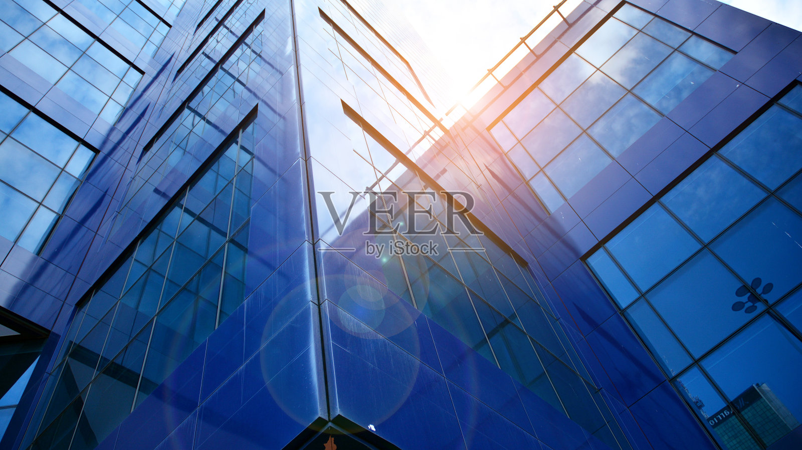 在晴朗的天空背景下，玻璃幕墙的现代办公大楼。照片摄影图片