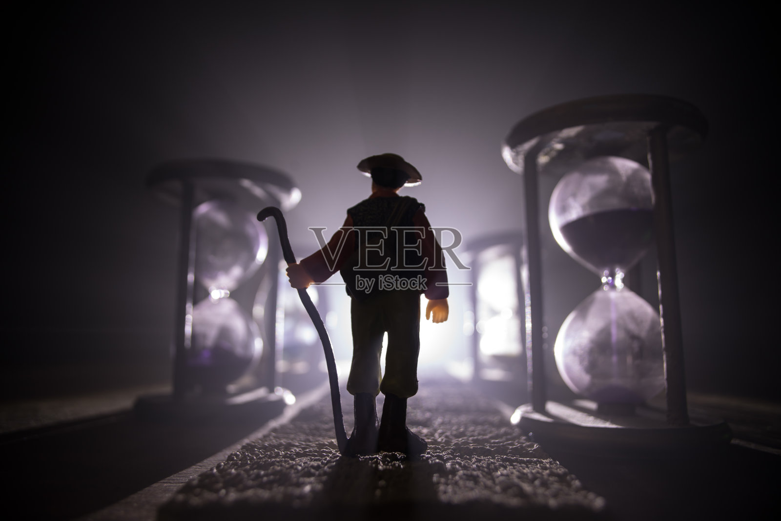 时间的概念。沙漏钟的剪影和带有箭头和烟雾的老式木钟，在深色的背景上配上热的黄橙色红蓝色冷背光，或者是带有复制空间的时间符号照片摄影图片