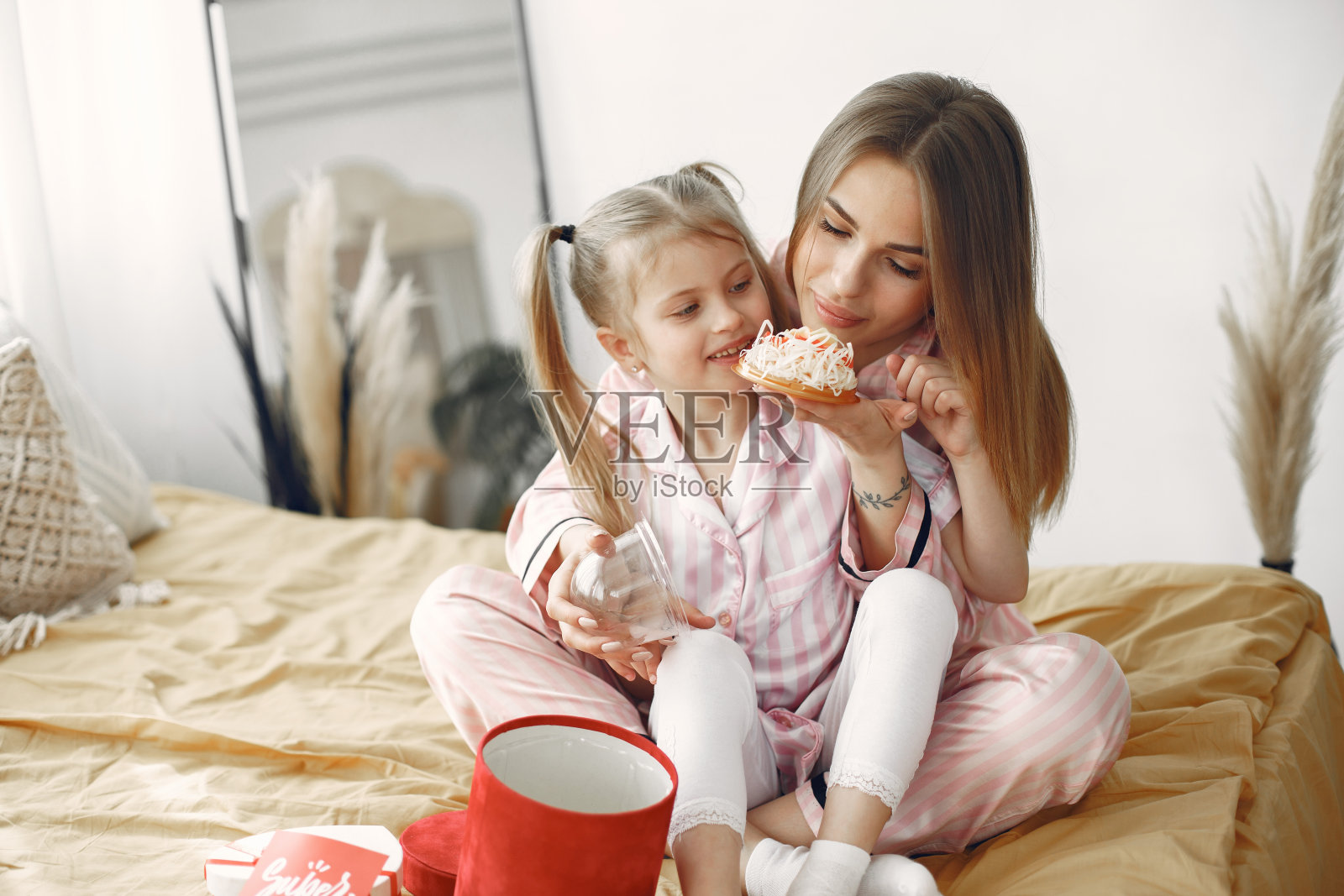 年轻的母亲和可爱的女儿在床上拥抱照片摄影图片