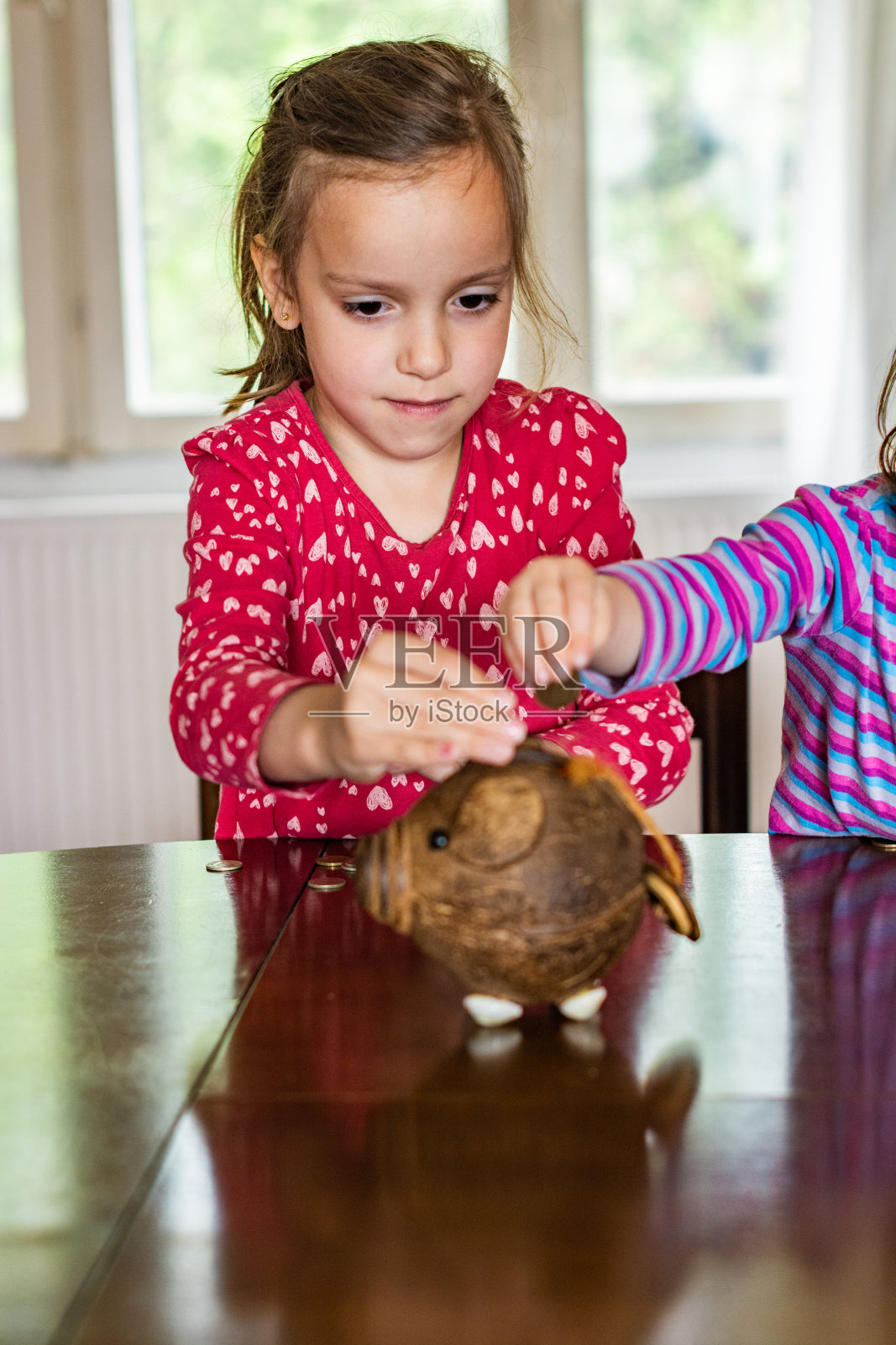小女孩在存钱罐里放硬币照片摄影图片