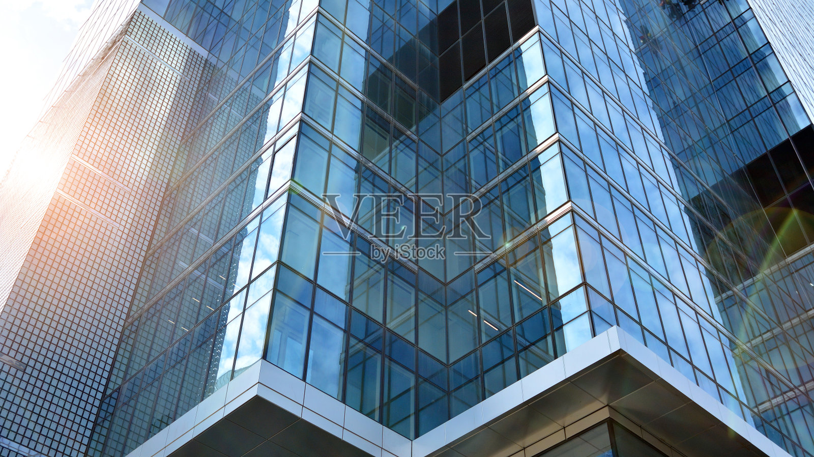 在晴朗的天空背景下，玻璃幕墙的现代办公大楼。照片摄影图片