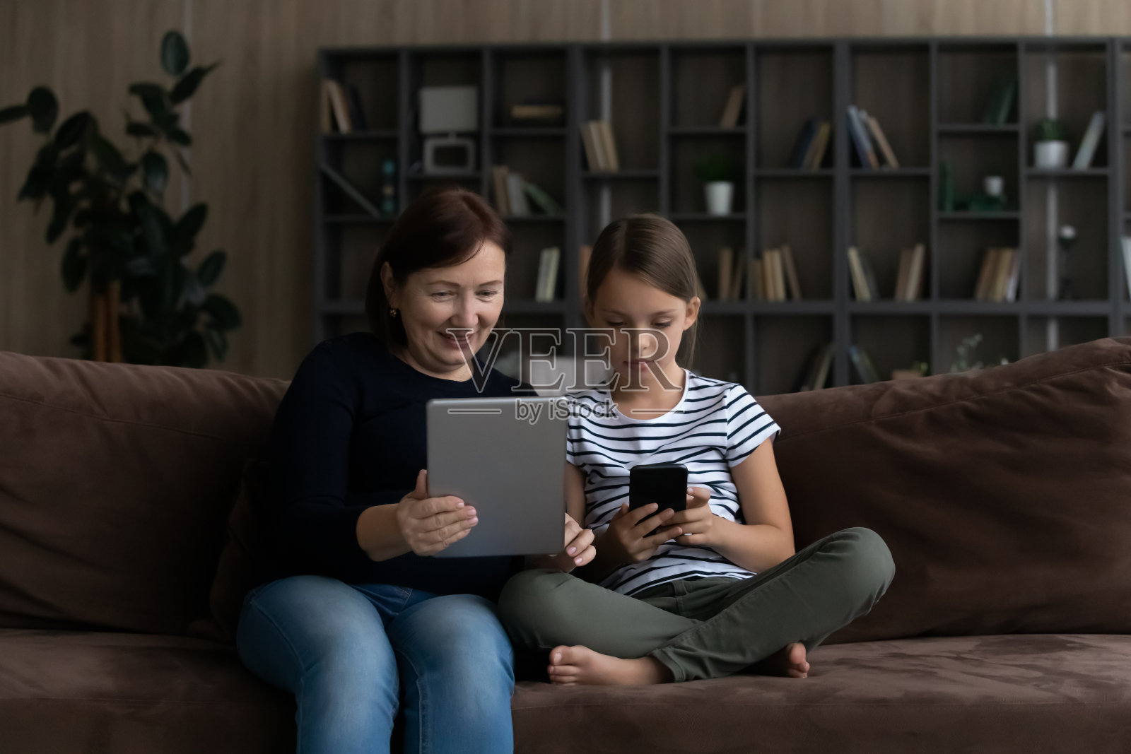 现代成熟的奶奶和十几岁的孙女使用小玩意照片摄影图片