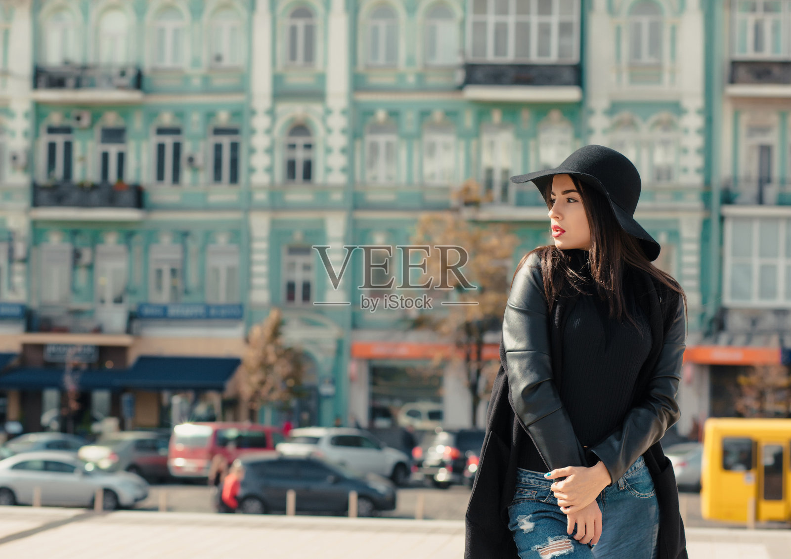 年轻漂亮女人的时尚肖像戴着宽边帽。在城市背景上摆姿势的女士照片摄影图片