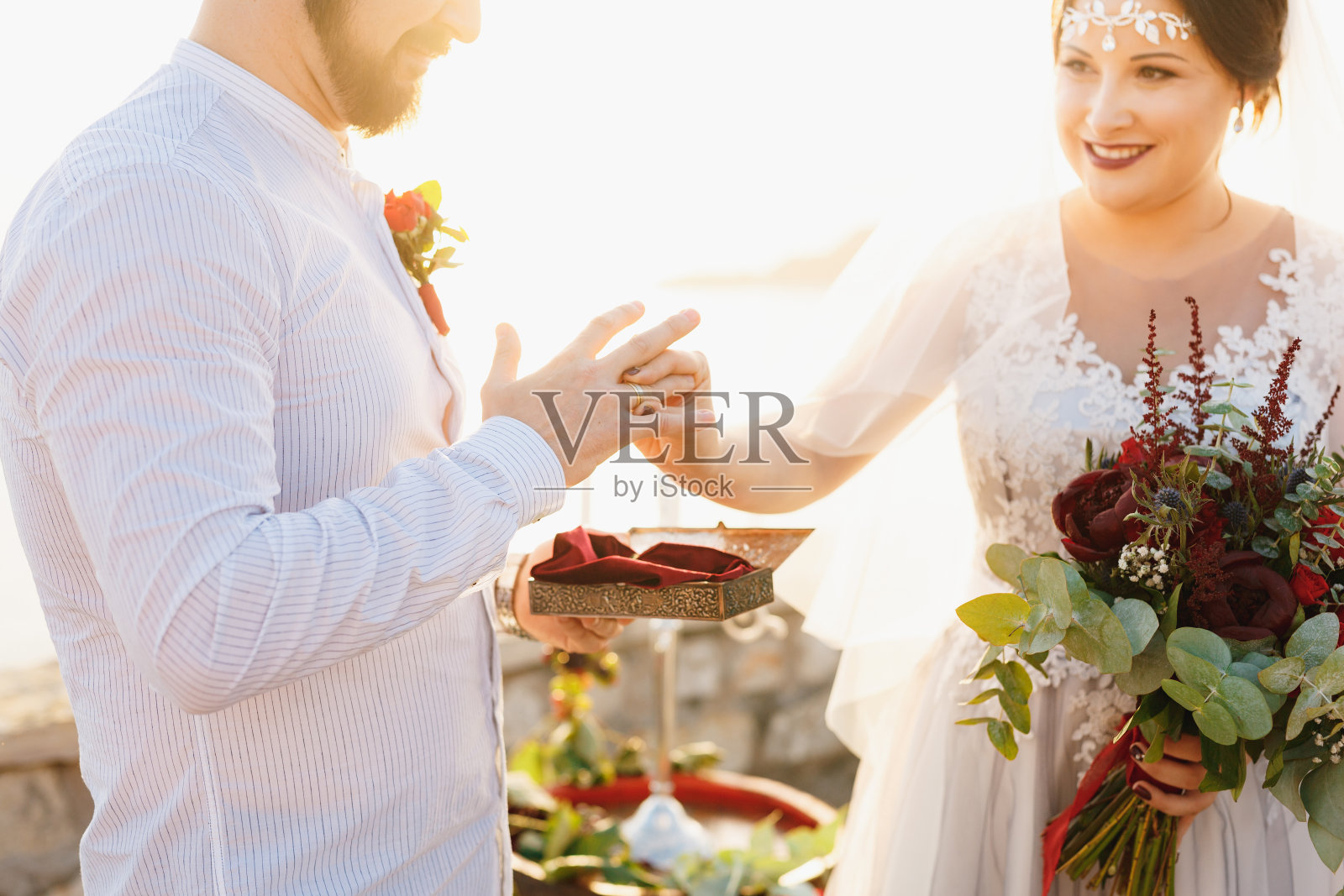 在婚礼上，新娘把戒指戴在新郎的手指上，手里拿着一束花照片摄影图片
