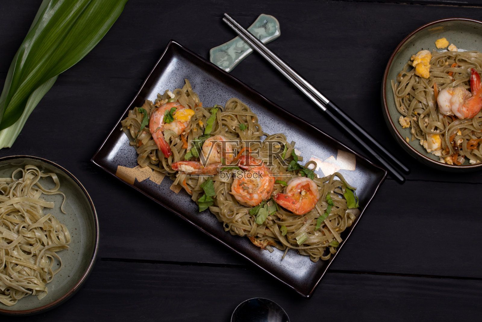 炸虾烧面条在黑色平铺菜。照片摄影图片