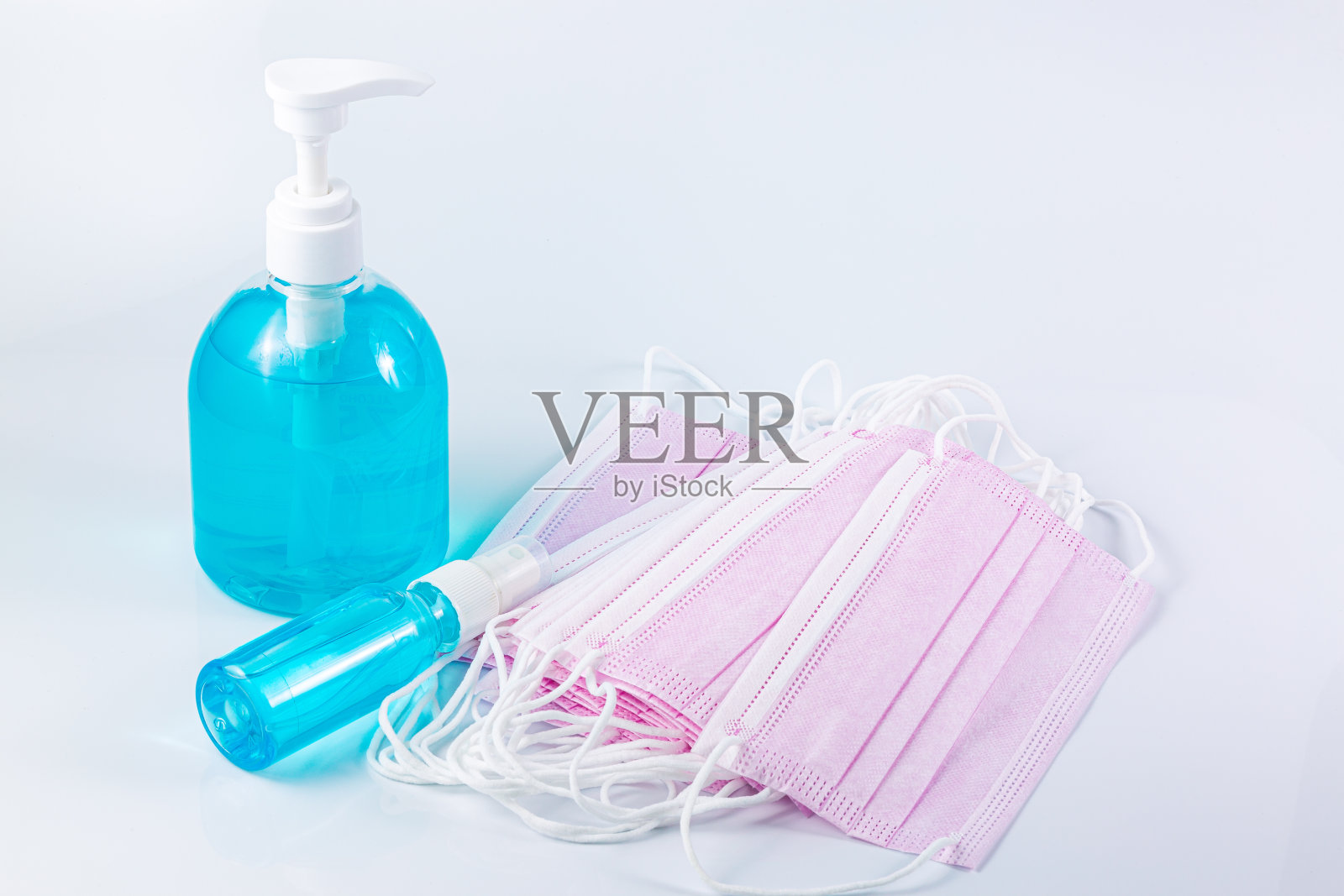 白色背景上的酒精和医用口罩，卫生口罩和酒精凝胶洗手液，白色背景上的抗菌和病毒，使用酒精凝胶洗手的人以预防COVID-19病毒照片摄影图片