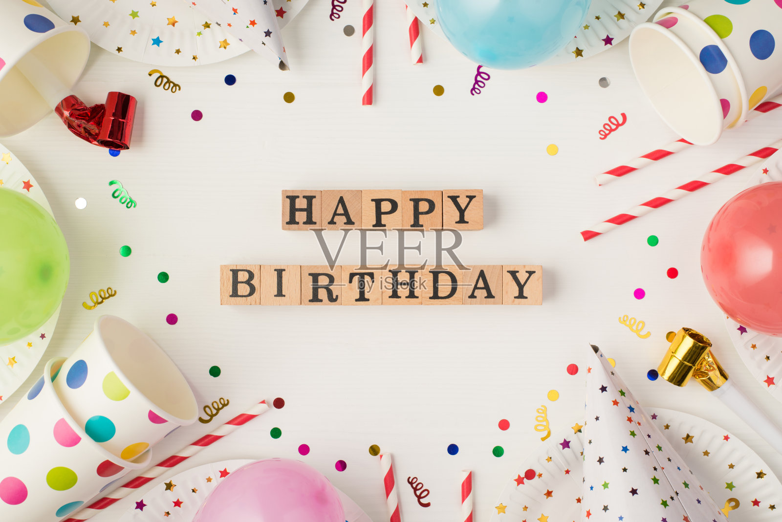 上面的照片杯子，盘子，纸屑，生日帽，派对，小管子，哨子，气球与题词生日快乐孤立在白色的背景照片摄影图片