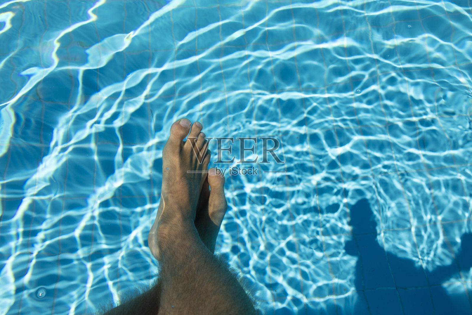 西班牙，夏天，一个年轻人在游泳池里的脚。照片摄影图片
