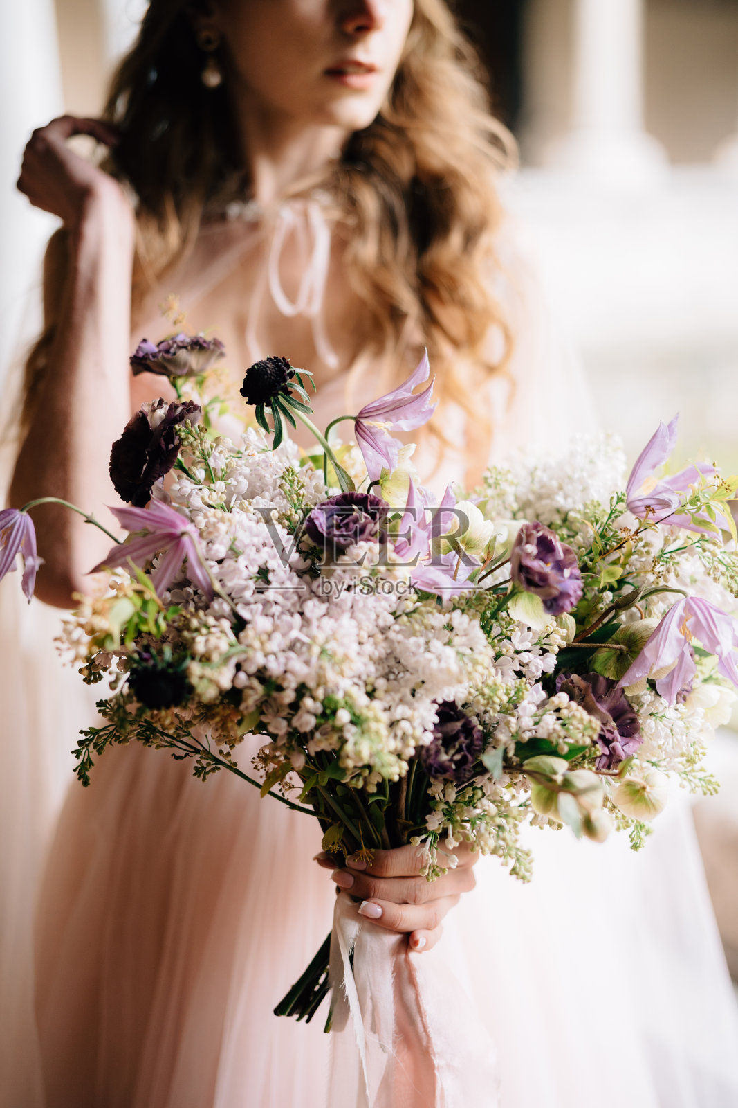 新娘穿着漂亮的粉红色连衣裙，手里拿着一束野花照片摄影图片