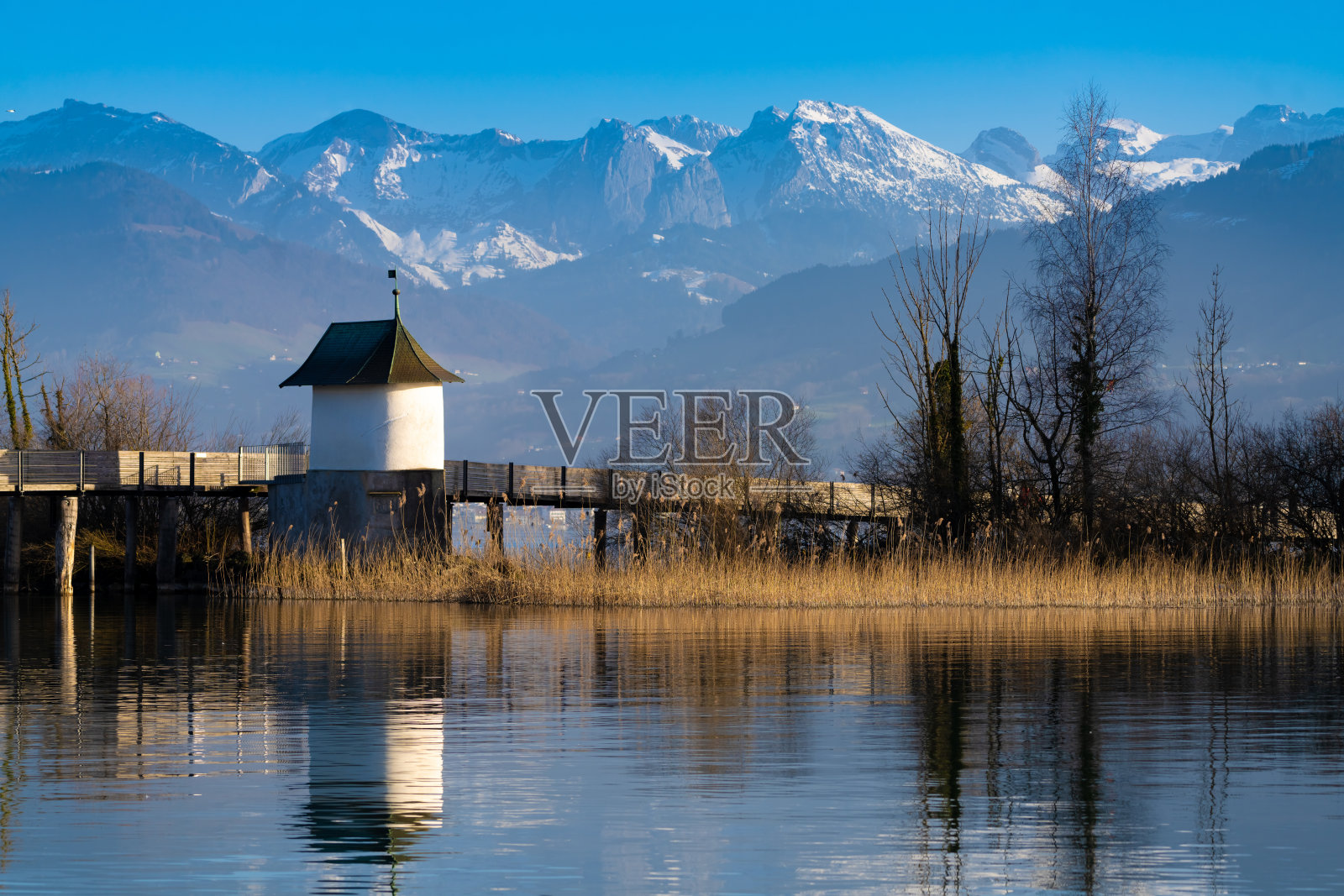 位于瑞士圣加伦rapperswill附近的上苏黎世湖(Obersee)的木制人行桥上，历史悠久的胡斯利教堂(圣詹姆斯之路)照片摄影图片